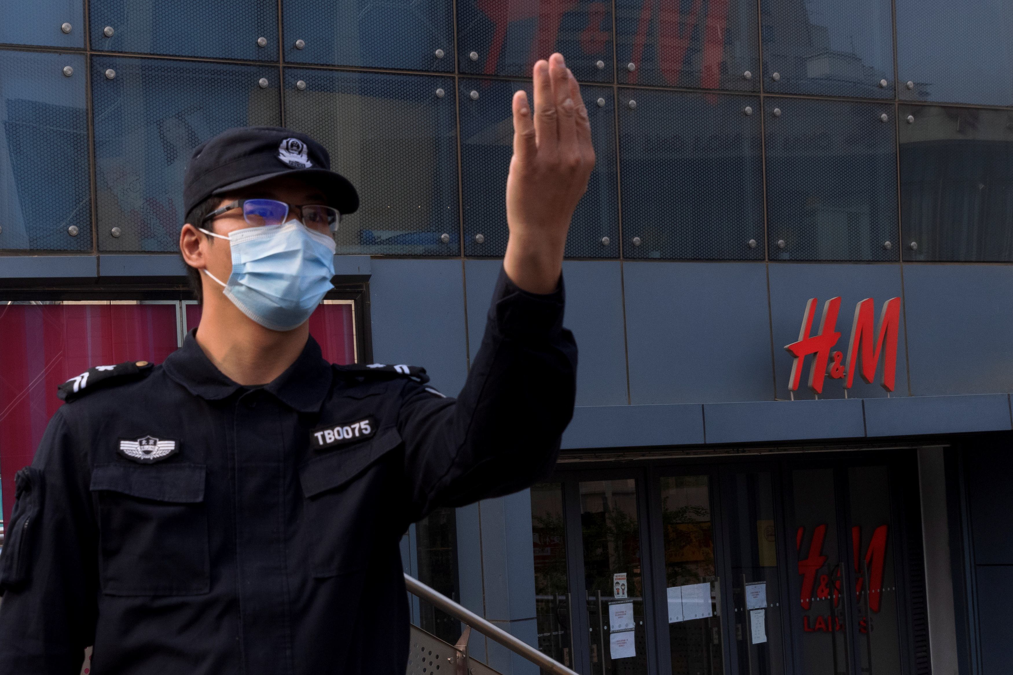 A police officer calls to colleagues for backup outside a store of the clothing giant H&M in a shopping area in Beijing