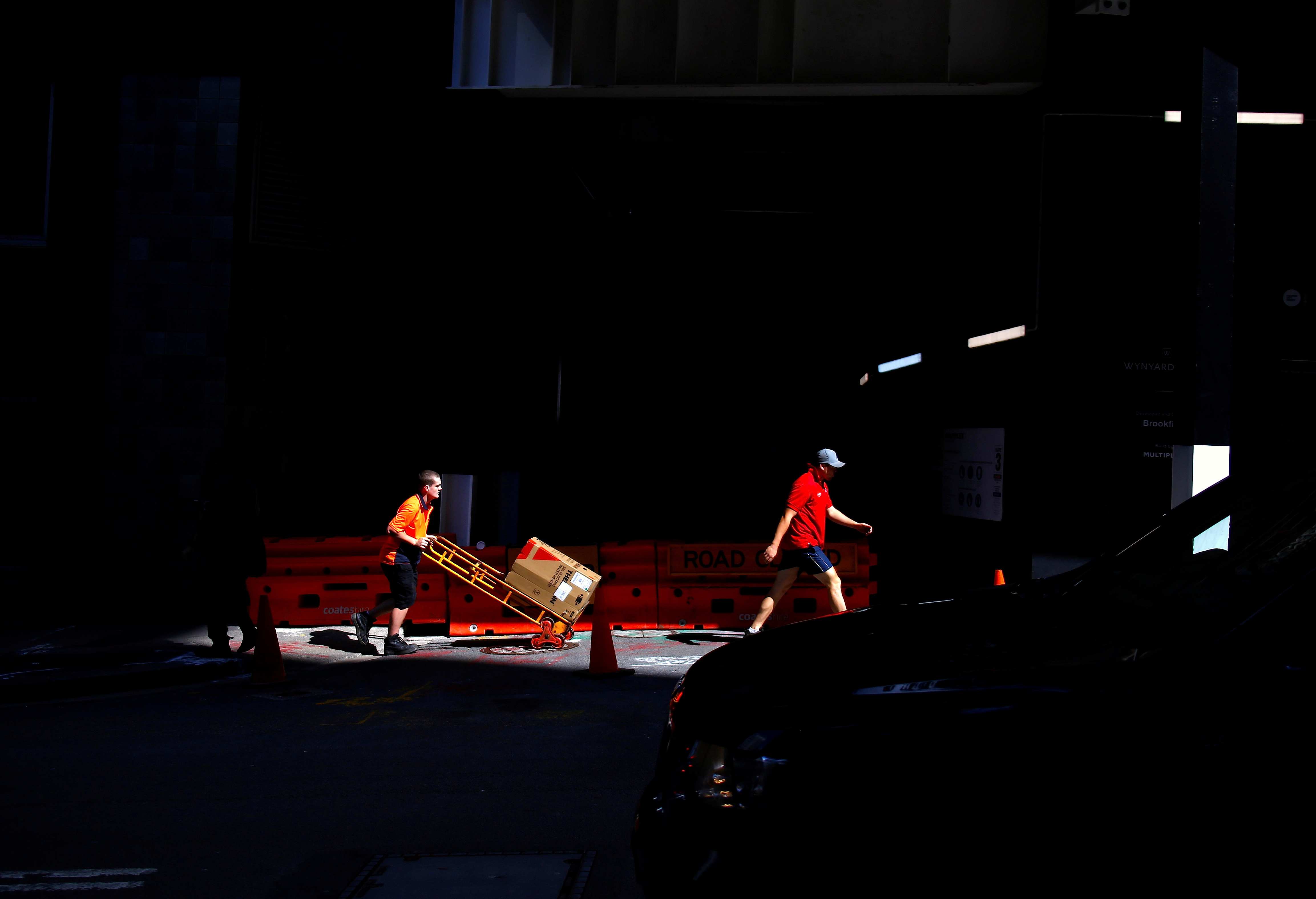 A worker pushes a trolley loaded with goods past a construction site in the central business district of Sydney