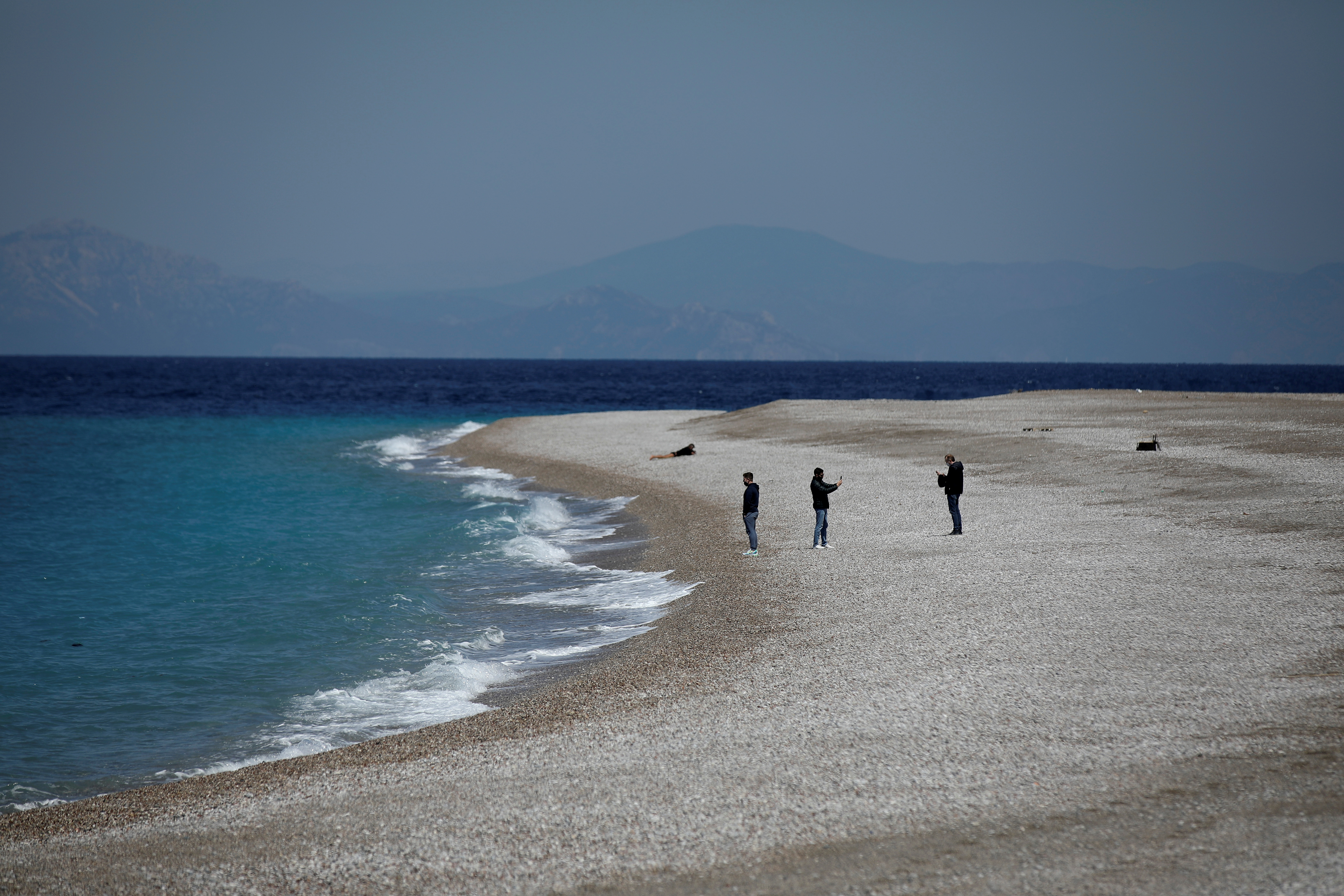 People stand on Elli Beach, amid the coronavirus disease (COVID-19) pandemic, on the island of Rhodes, Greece, April 12, 2021. REUTERS/Louiza Vradi/File Photo