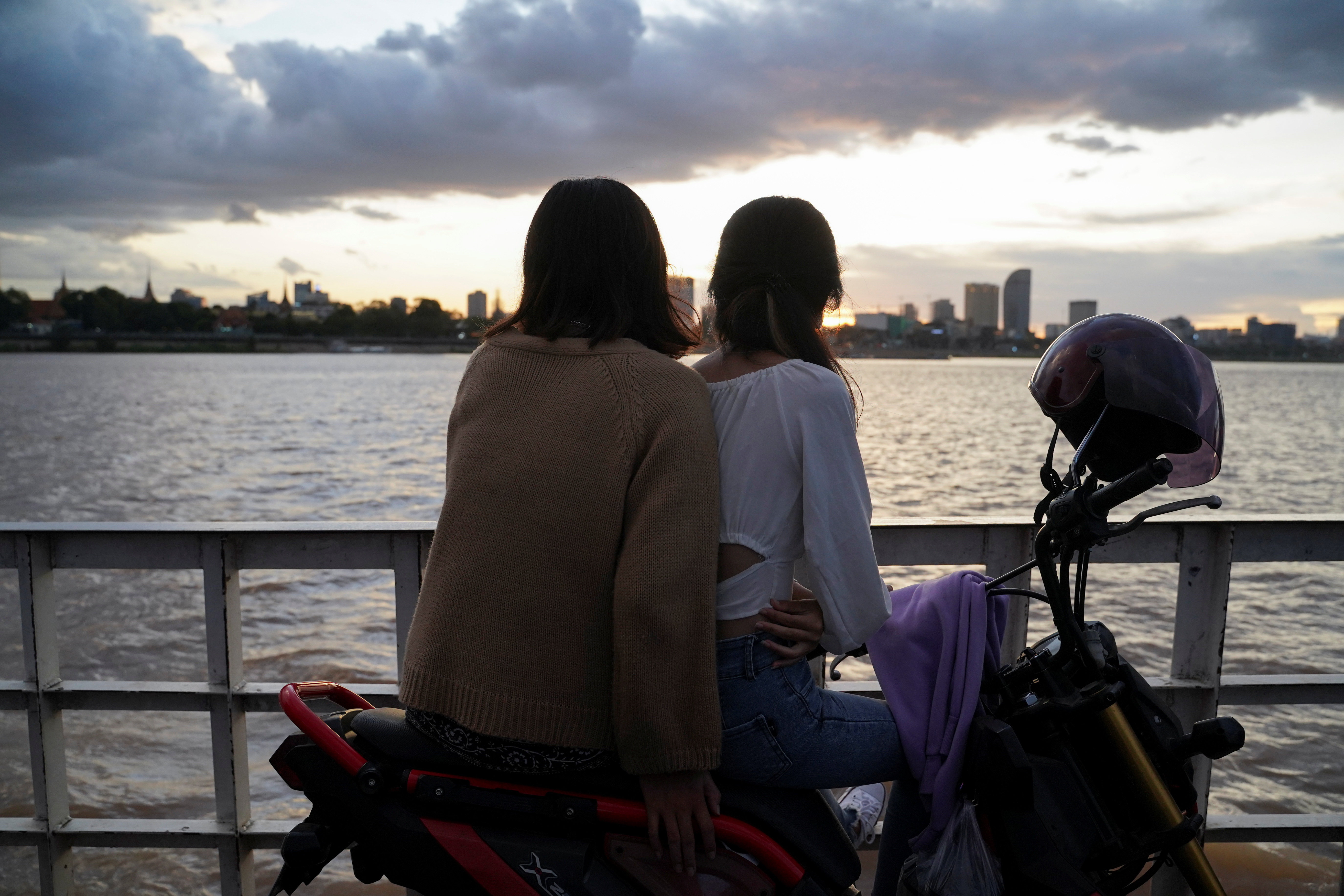 People ride a ferry at sunset on the Mekong River in Phnom Penh