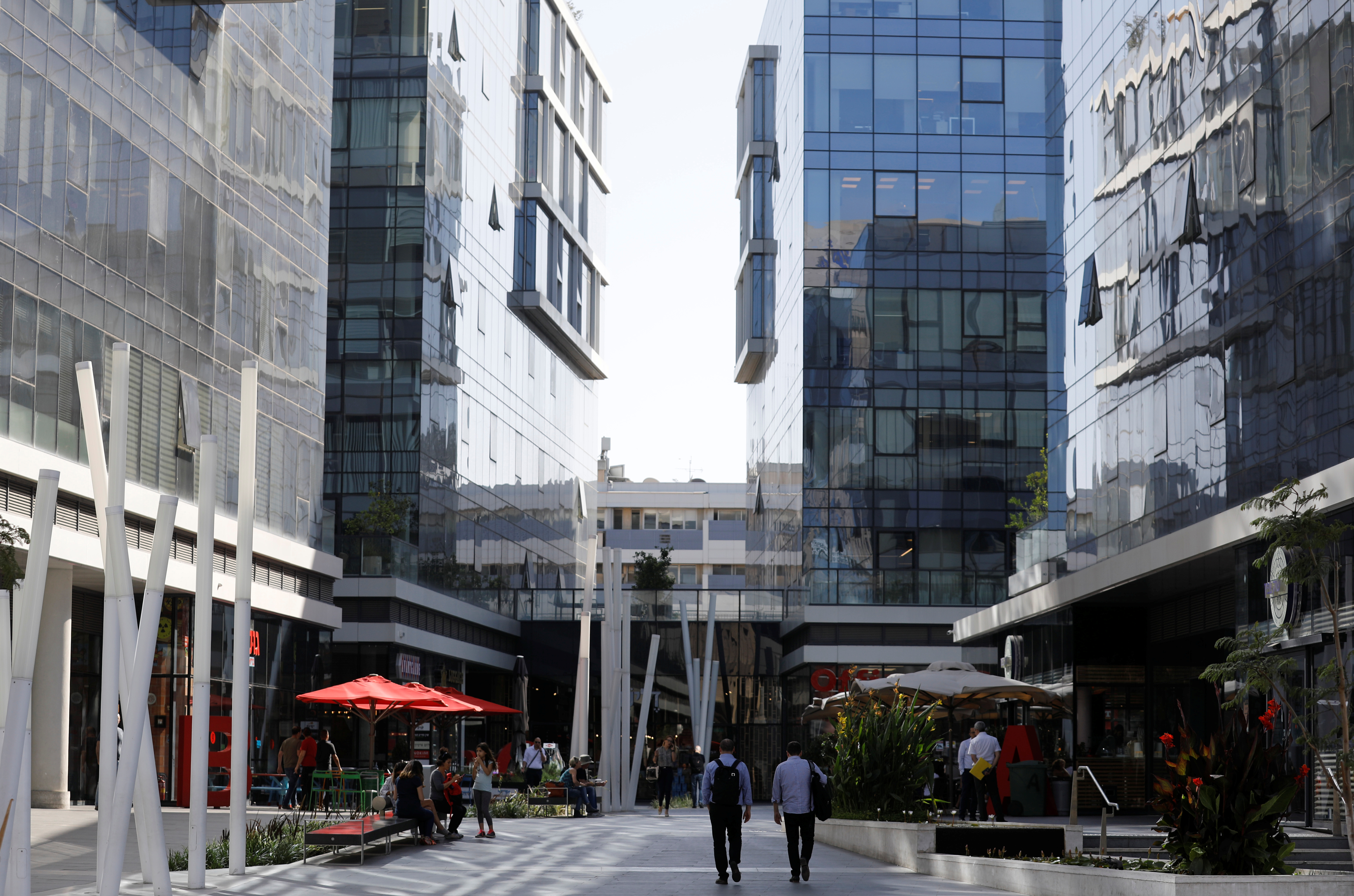 Men walk near high-rise buildings in the high-tech business area of Tel Aviv