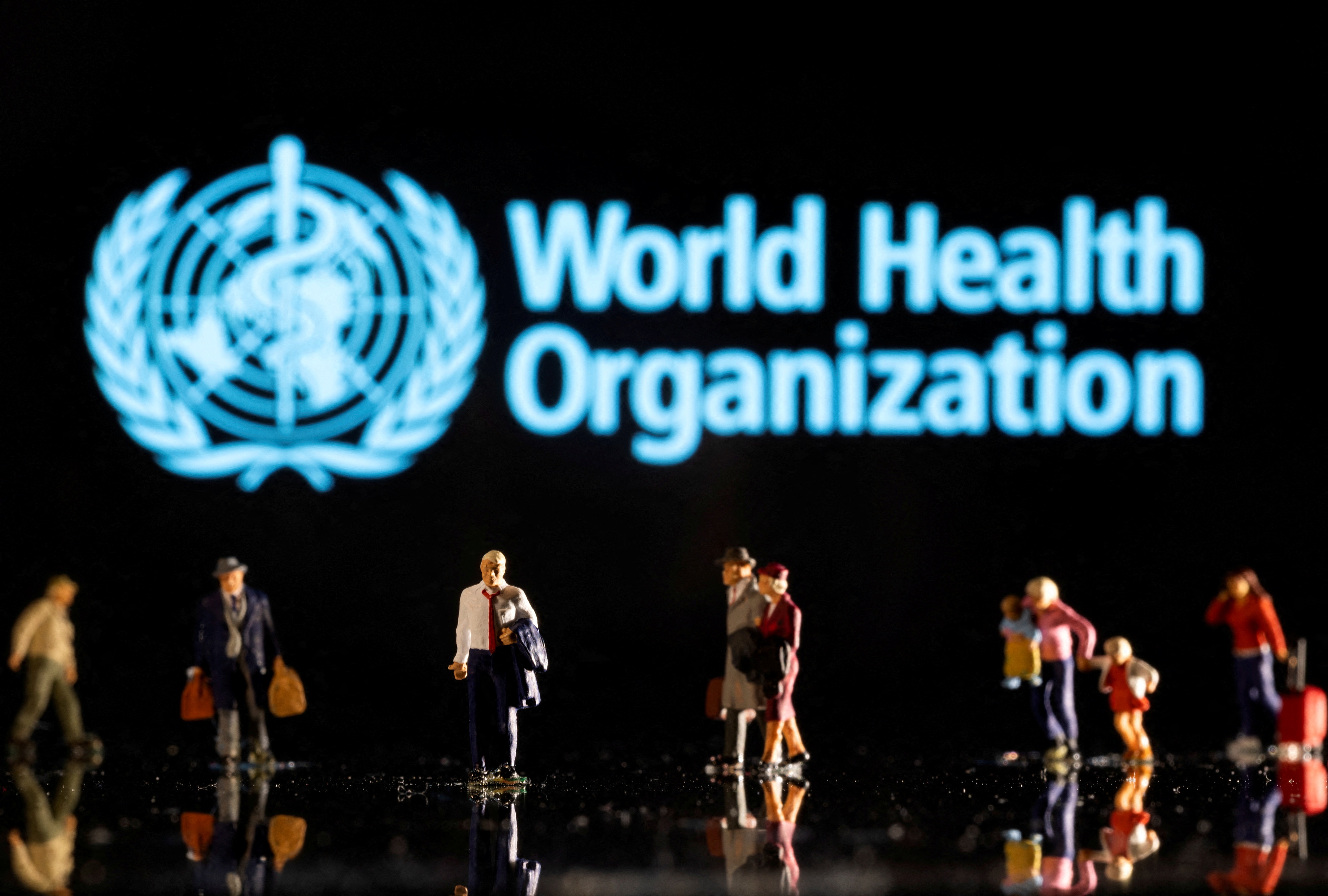 Illustration shows small figurines and displayed World Health Organization logo