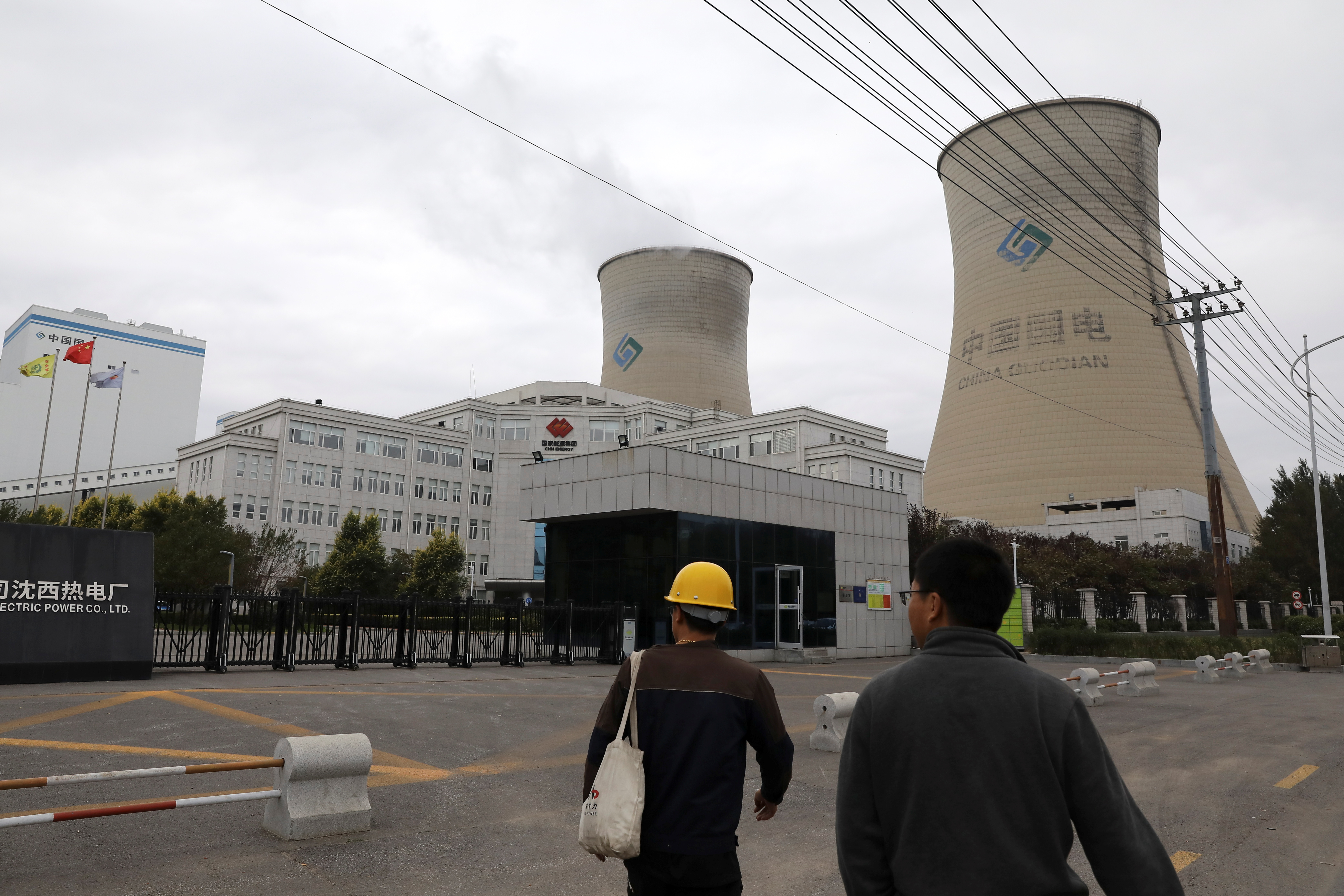 People walk past a coal-fired power plant in Shenyang