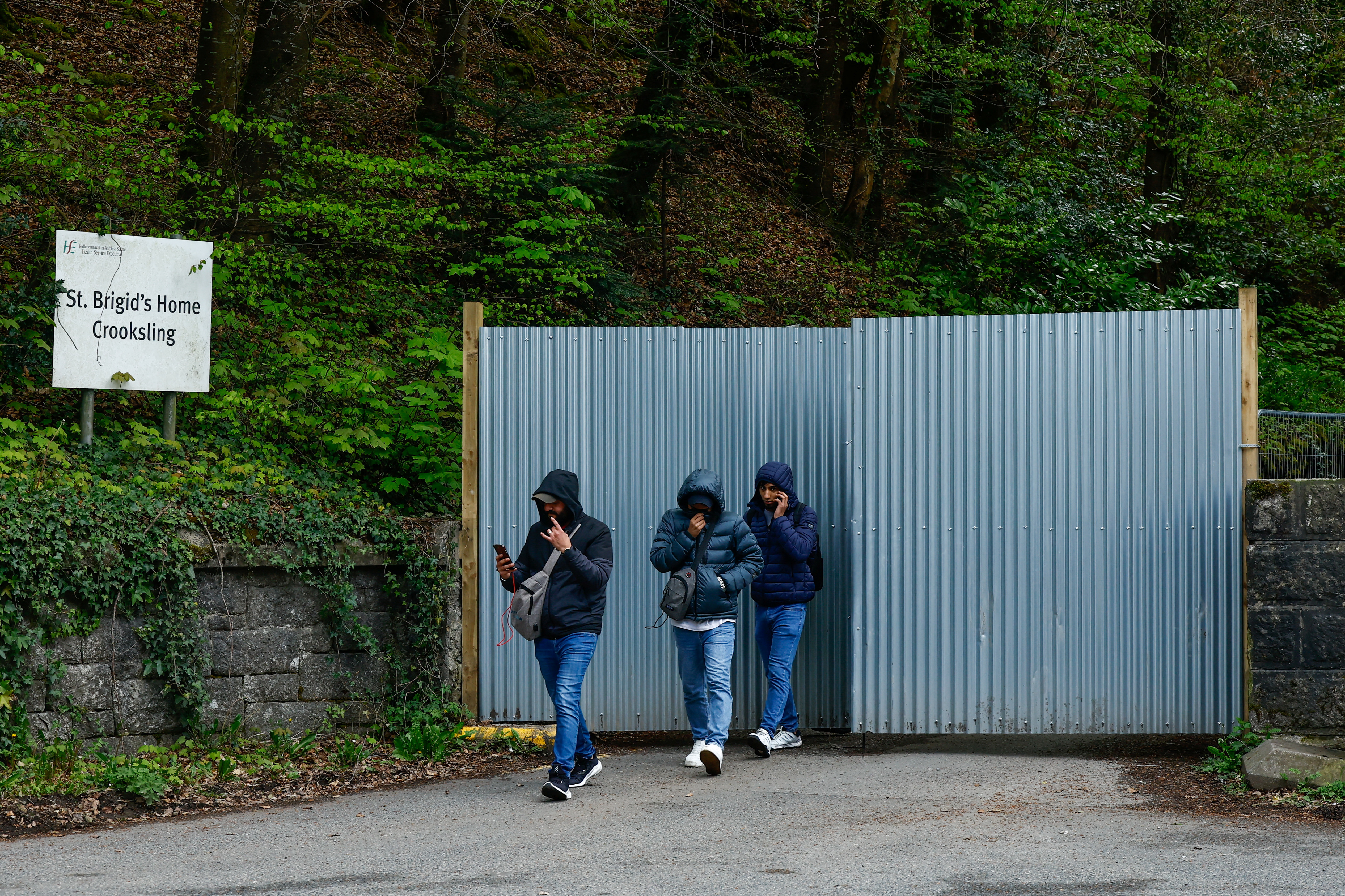 Asylum seekers walk past the gate of an IPAS tented accommodation service, in Crooksling