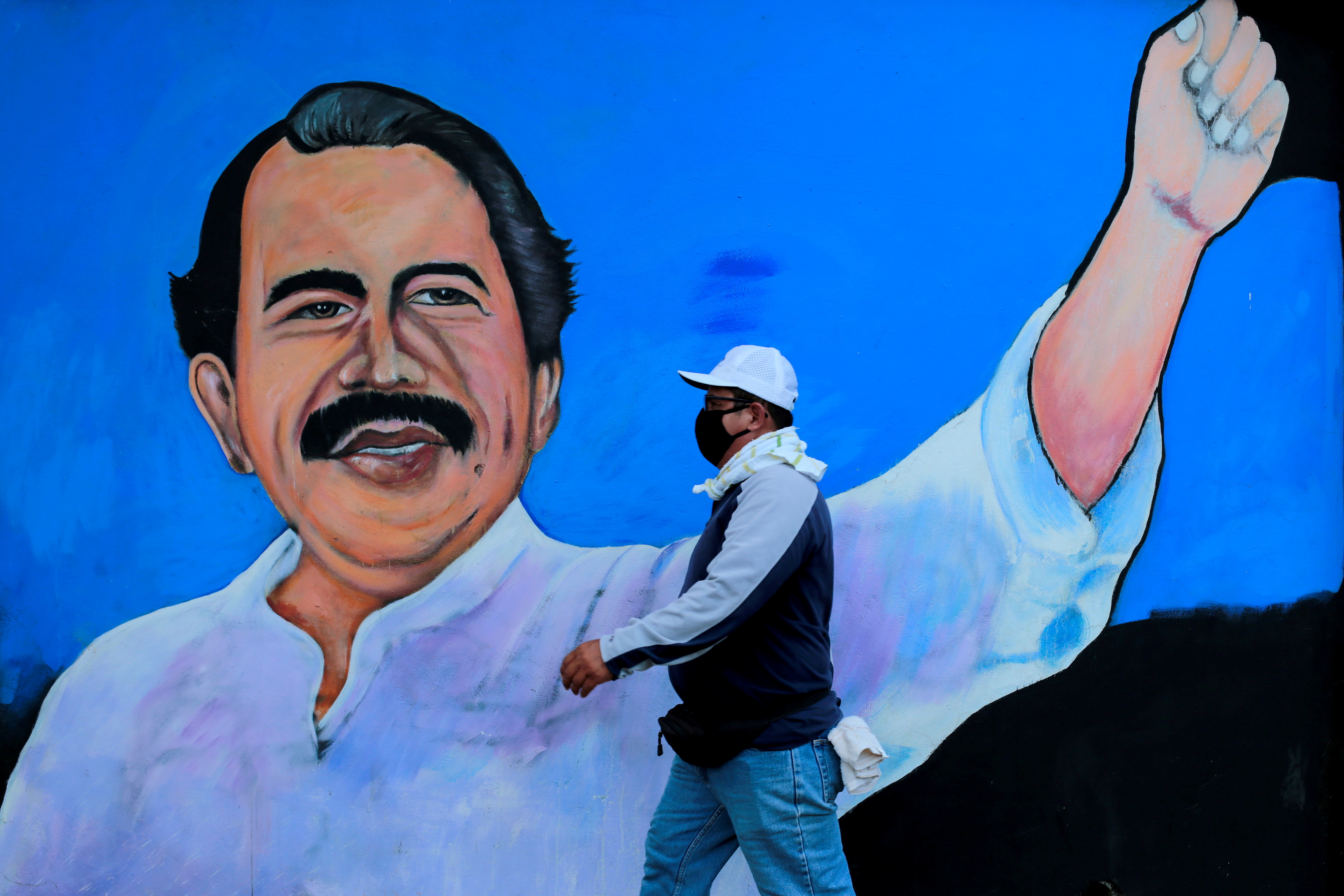 mFILE PHOTO: FILE PHOTO: FILE PHOTO: A man, wearing a face mask for protection against the coronavirus disease (COVID-19), walks by a mural depicting Nicaraguan President Daniel Ortega, in Managua, Nicaragua March 30, 2020.
