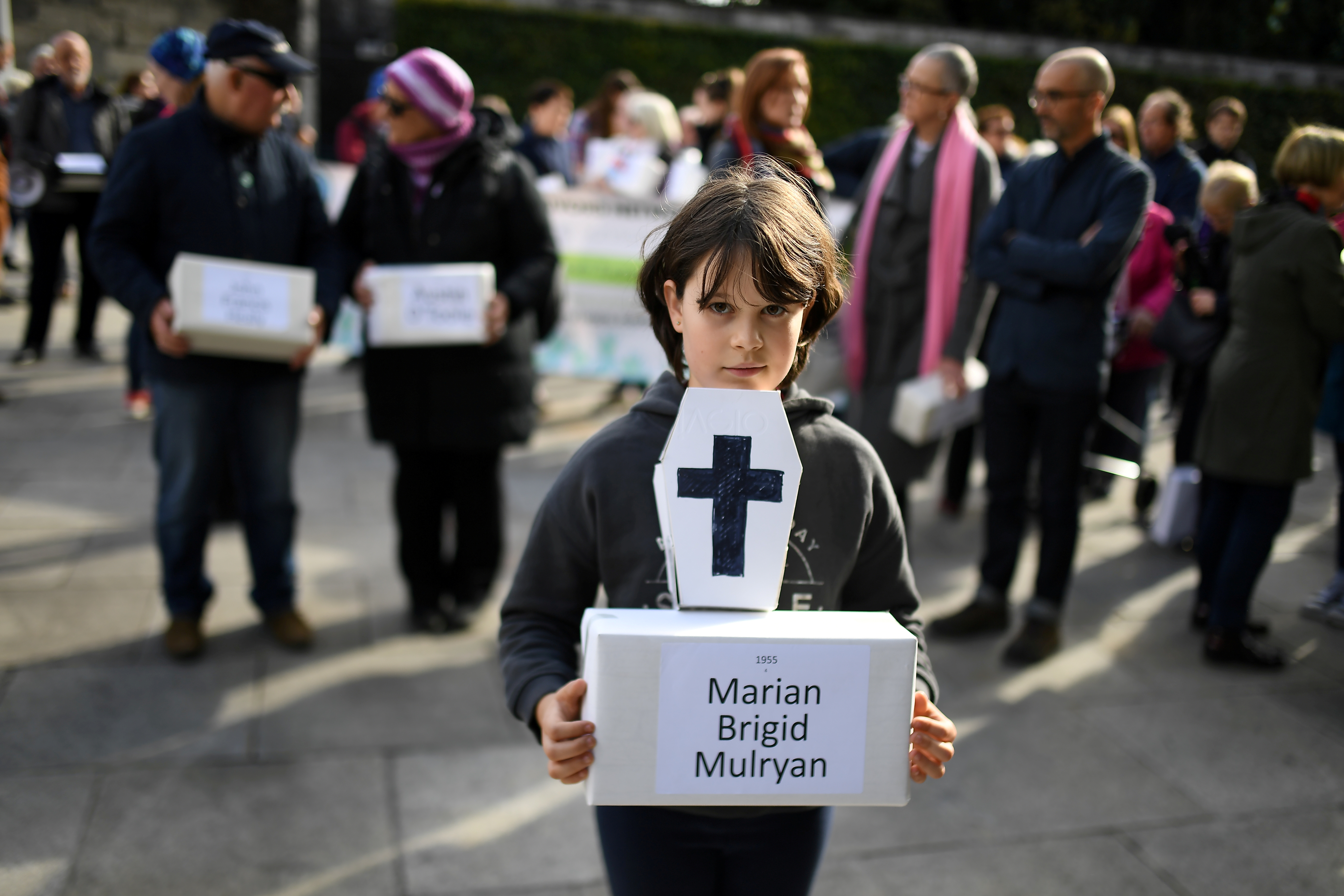 Matilda Kelly holds a funeral box at a funeral procession in remembrance of the bodies of the infants discovered in a septic tank, in 2014, at the Tuam Mother and Baby Home, in Dublin