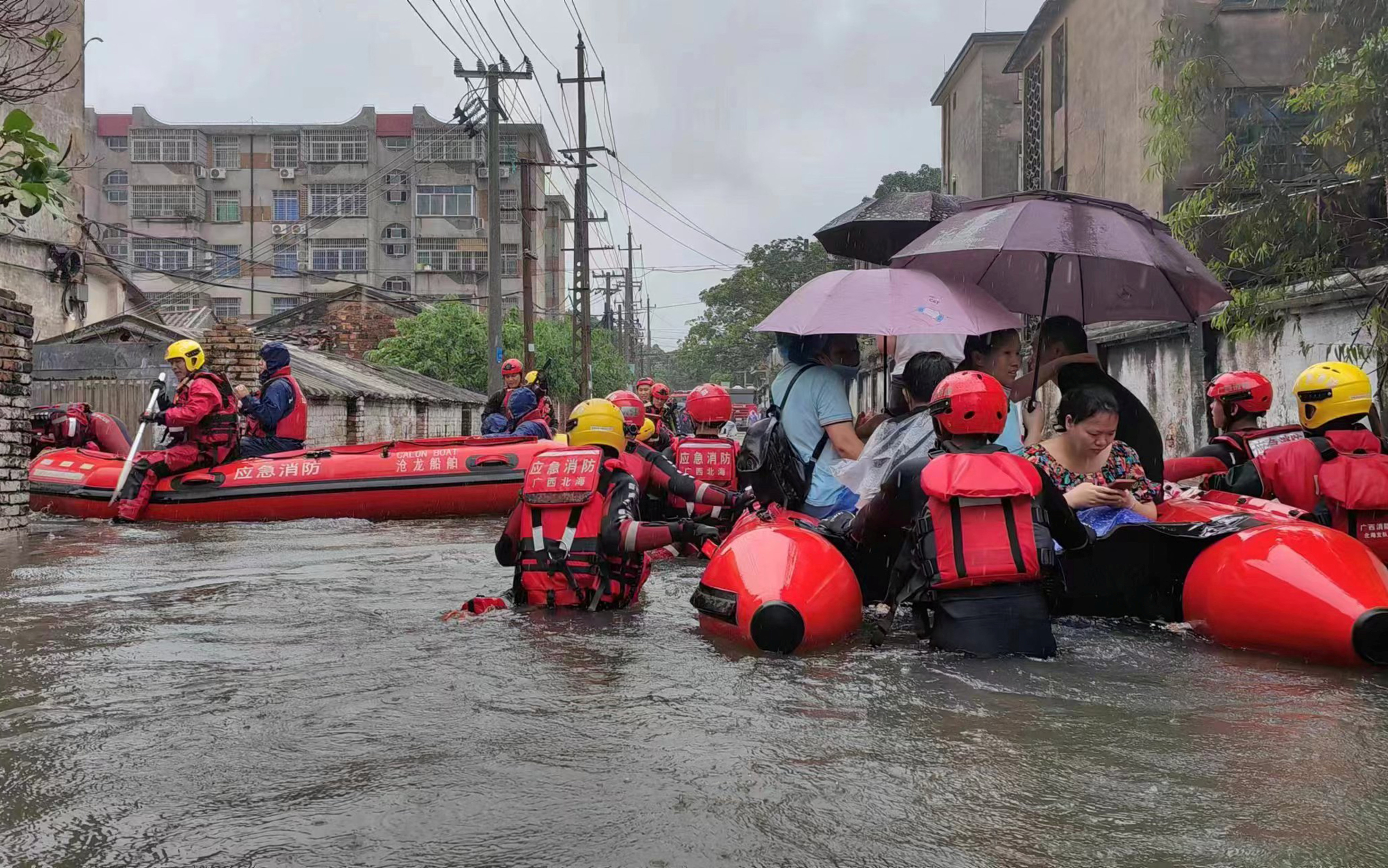 Rescue workers evacuate stranded residents on a flooded street following heavy rainfall in Beihai