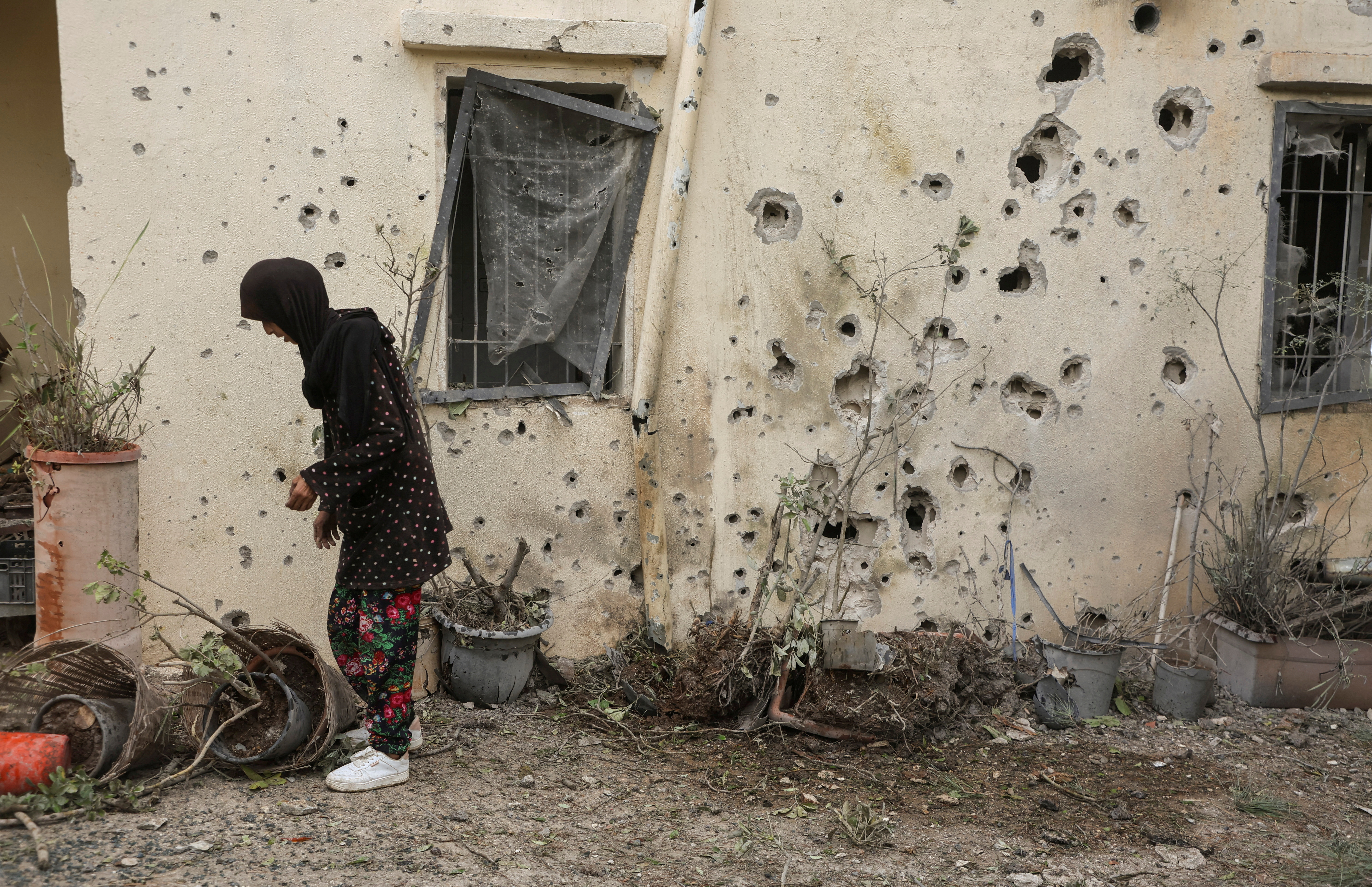 A woman stands near a bullet-riddled wall in Zahajra, near the border with Israel