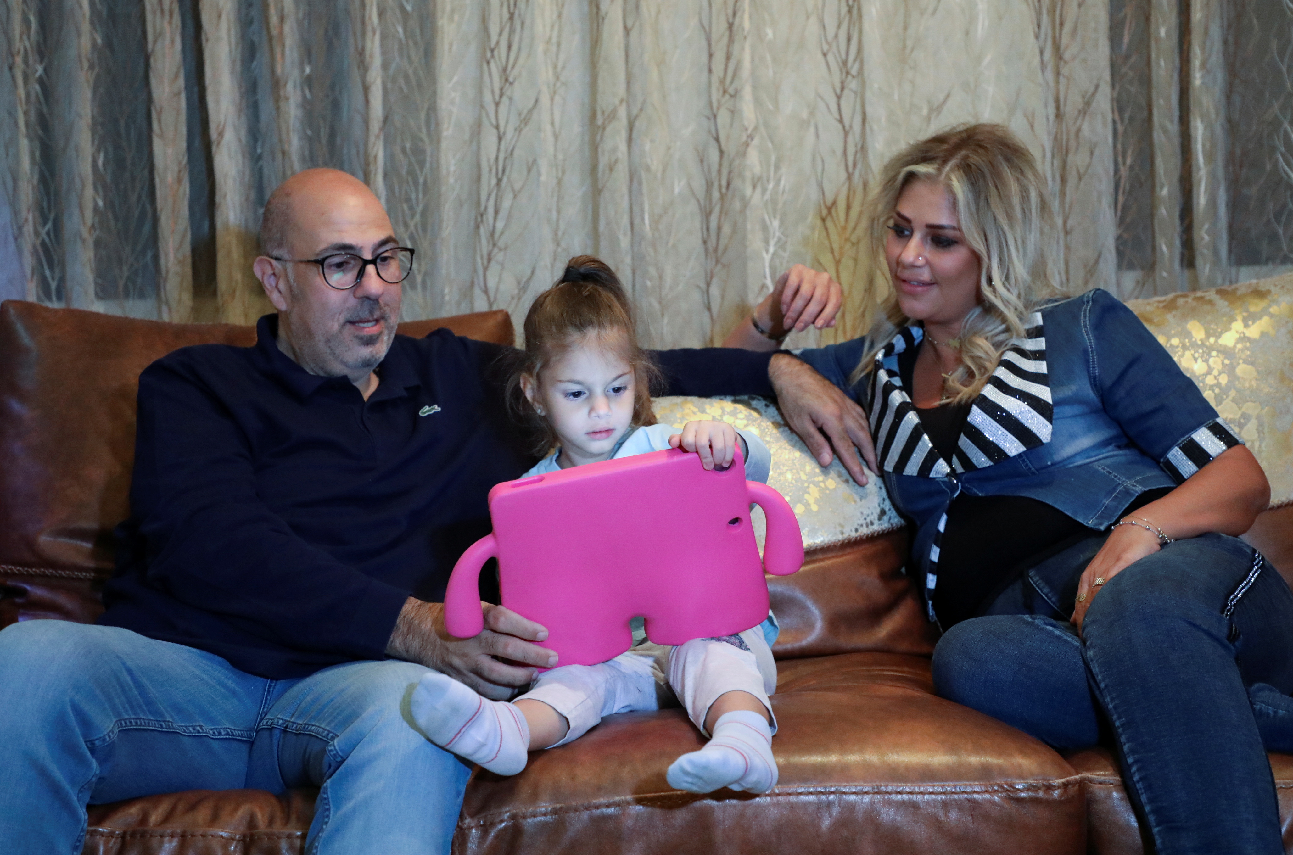 Ralph Khoury, 44, sits with his wife and one of his two daughters, during an interview with Reuters at his home in Qornet El Hamra, Lebanon, September 24, 2021. REUTERS/Mohamed Azakir