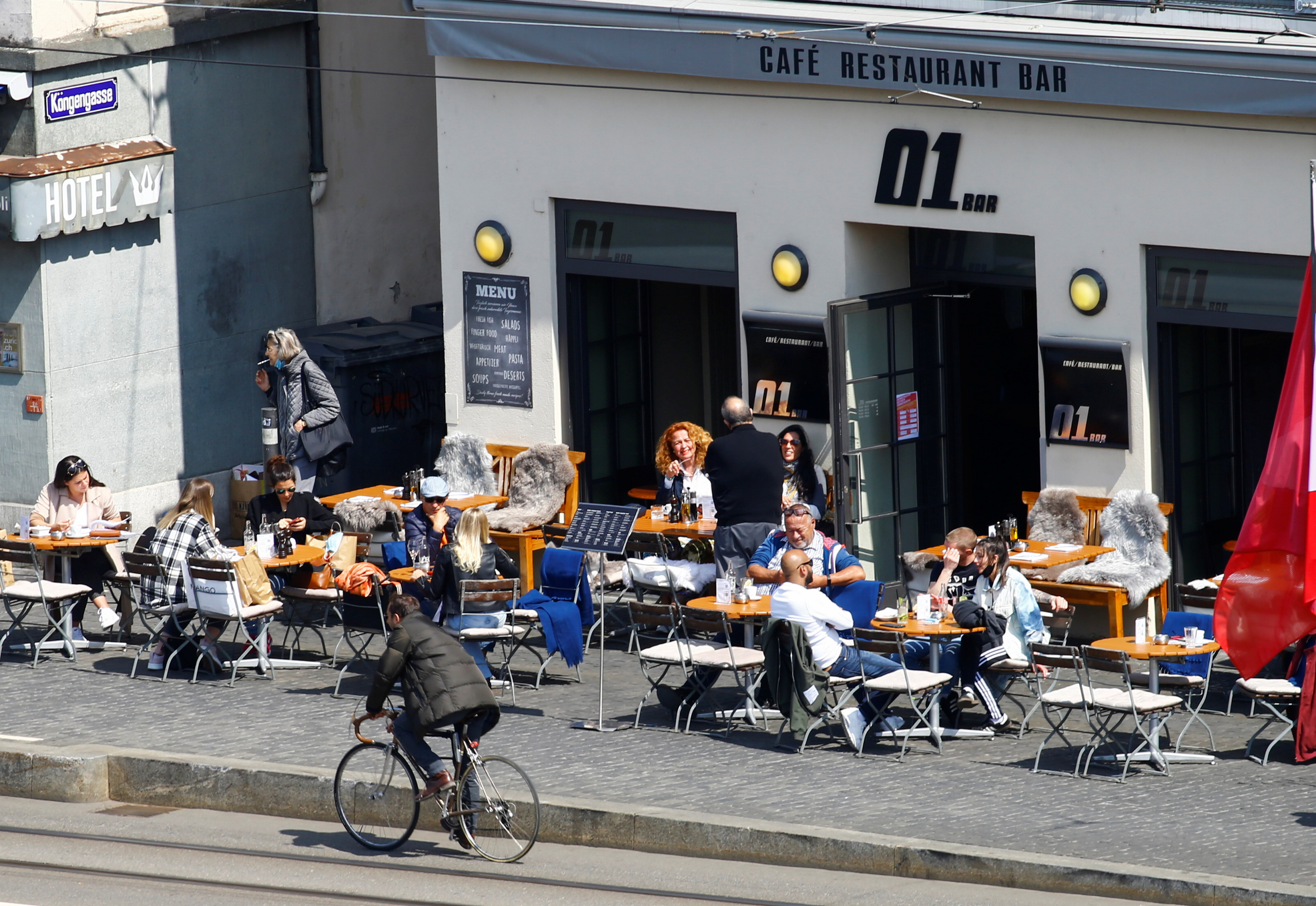 Guests enjoy the sunny weather as they sit in front of a restaurant after Swiss government allowed to reopen outdoor terraces, as the spread of the coronavirus disease (COVID-19) continues, on Muensterhof square in Zurich, Switzerland April 20, 2021. REUTERS/Arnd Wiegmann/Files