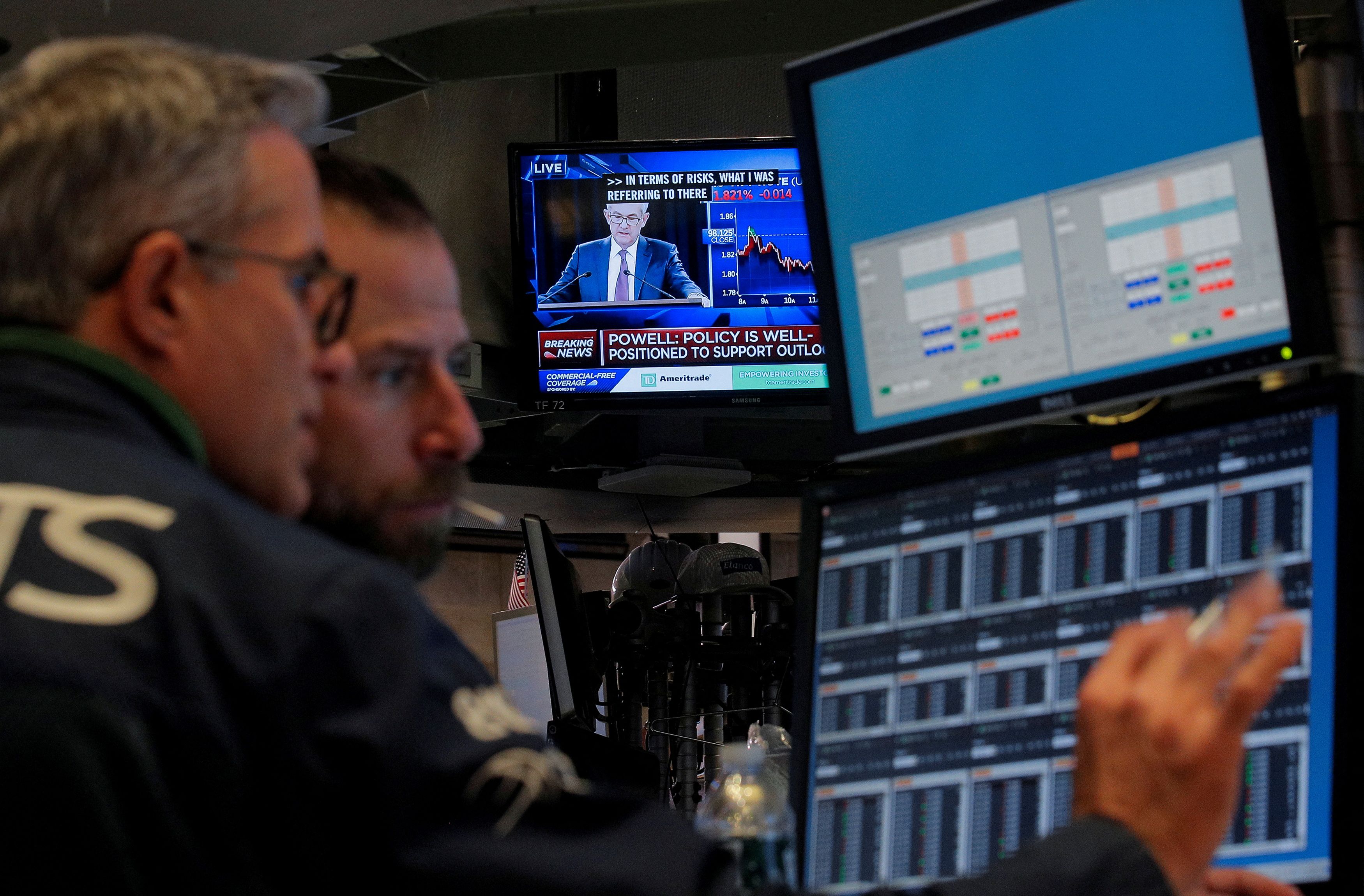 FILE PHOTO: Traders work as a screen shows Federal Reserve Chairman Jerome Powell's news conference after the U.S. Federal Reserve interest rates announcement on the floor of the  NYSE in New York