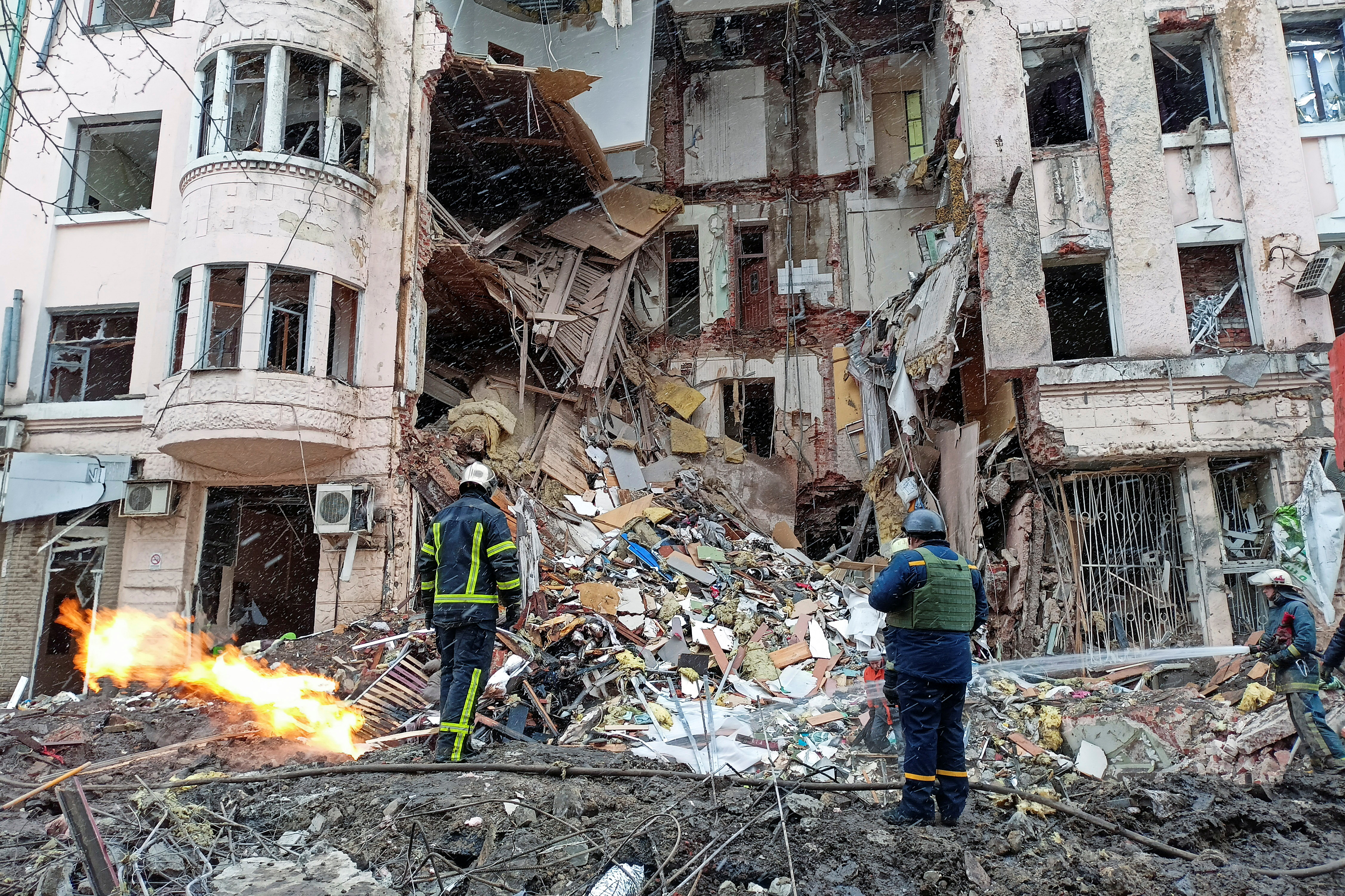 Rescuers work next to a building damaged by air strike in Kharkiv