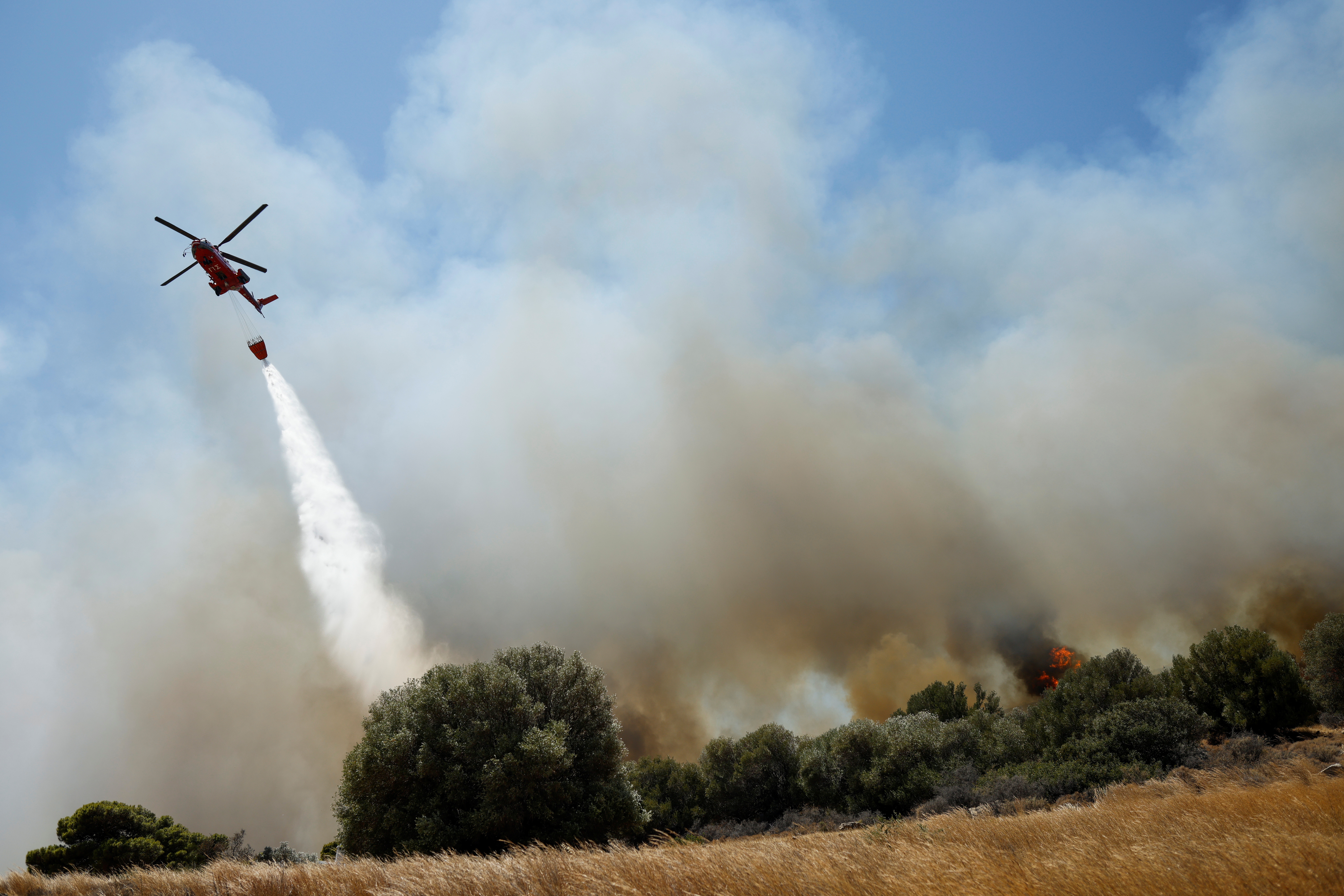 Un helicóptero contra incendios fai caer unha auga cando se queima un incendio na aldea de Markati, preto de Atenas, Grecia, o 16 de agosto de 2021. REUTERS / Alkis Konstantinidis
