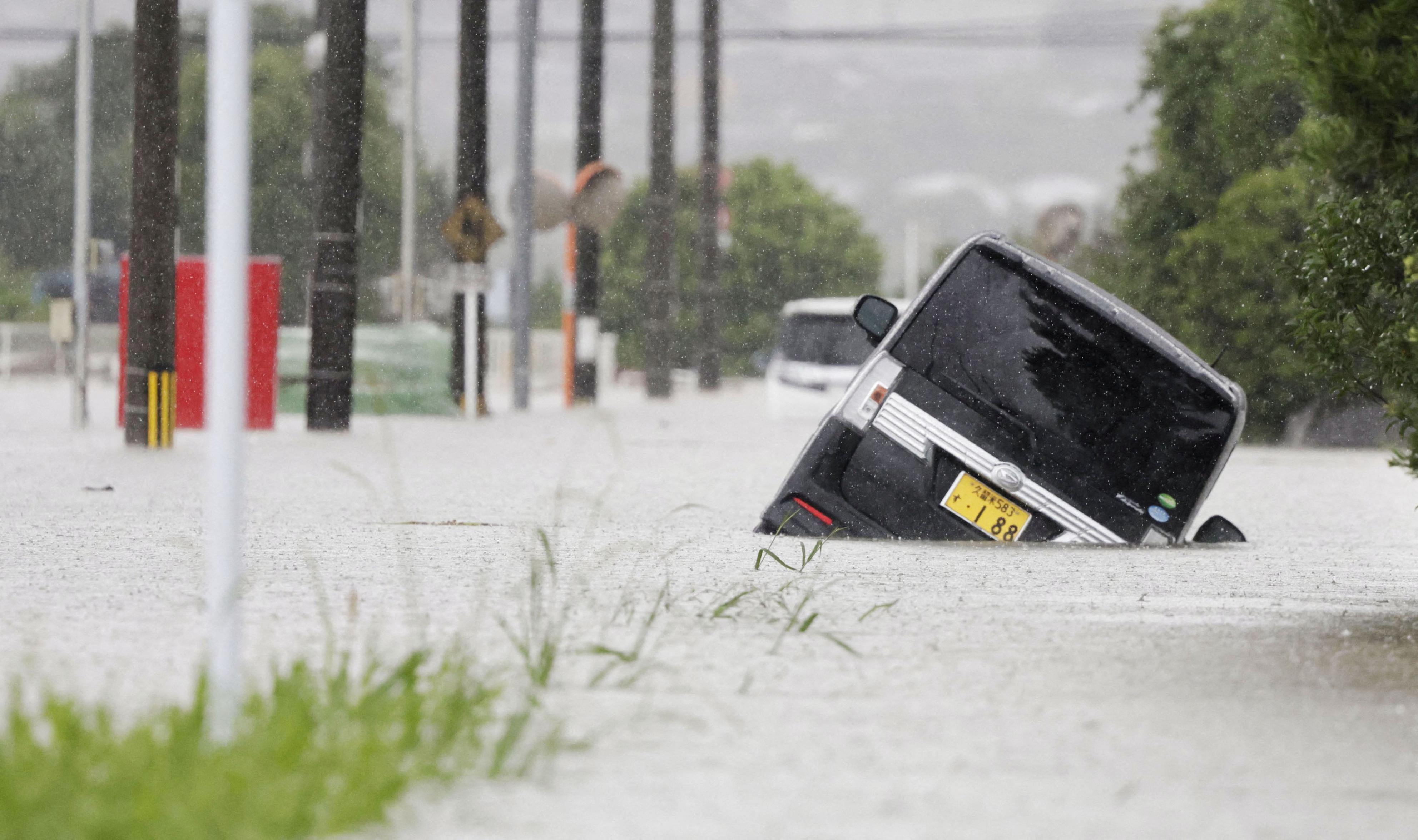Cars are stranded in a flooded road in heavy rain in Kurume