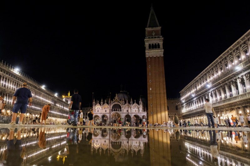 People walk in a flooded St. Mark's Square during an exceptional high water in Venice, Italy August 8, 2021. Picture taken August 8, 2021. REUTERS/Manuel Silvestri