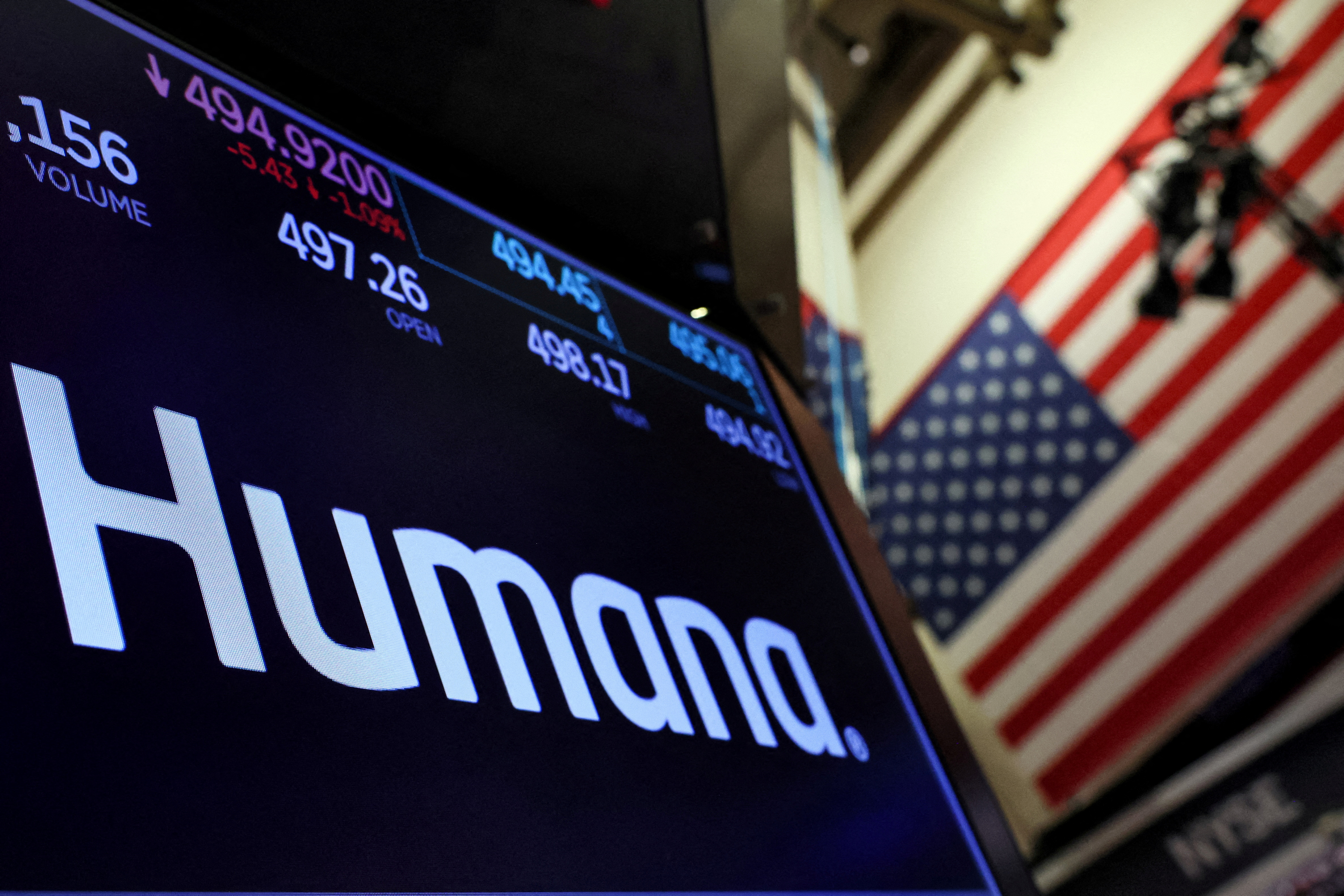 A screen displays the logo and trading information for Humana on the floor of the NYSE in New York
