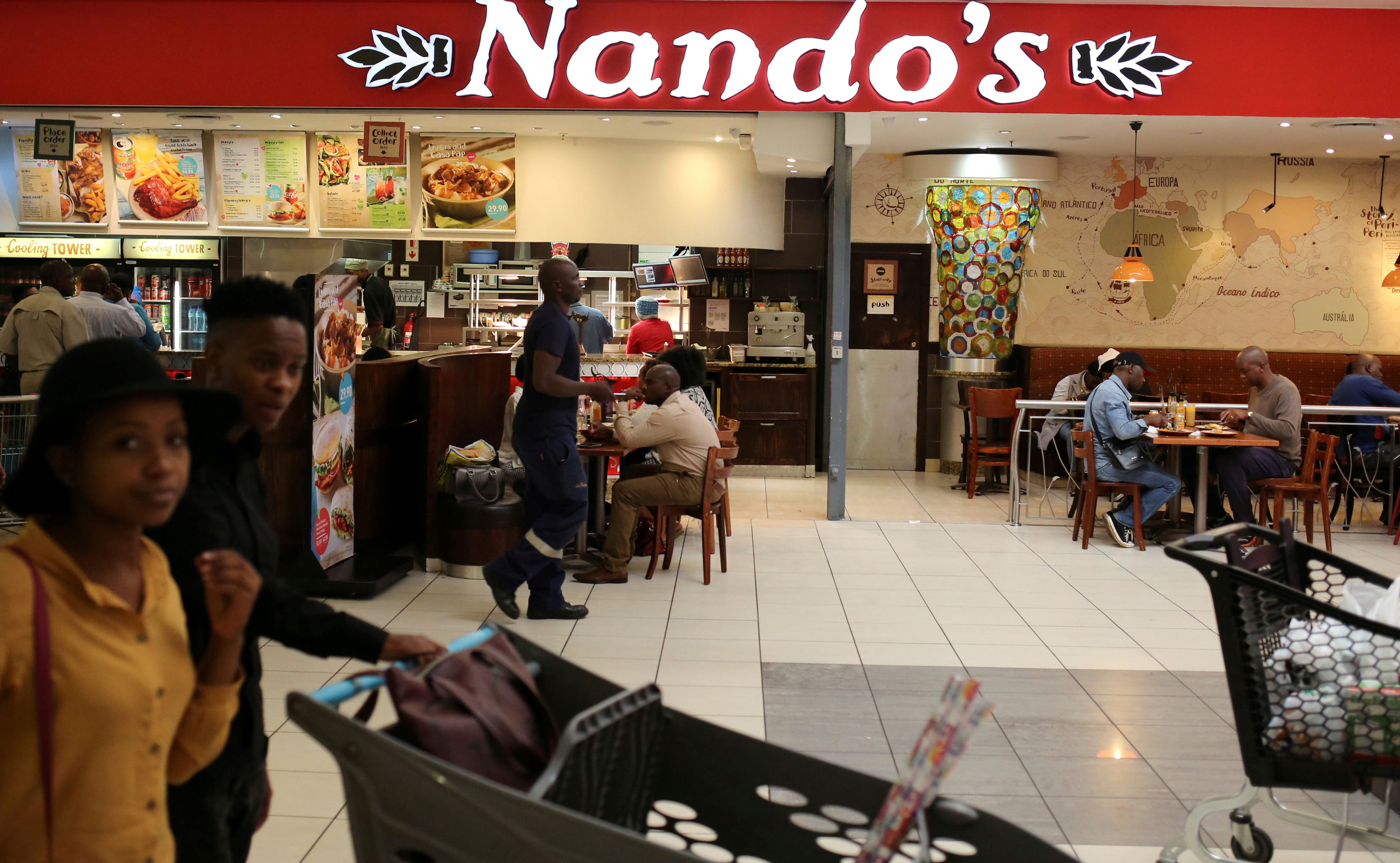 Shoppers walk past South African fast-food chain Nandos at a mall in Johannesburg, South Africa