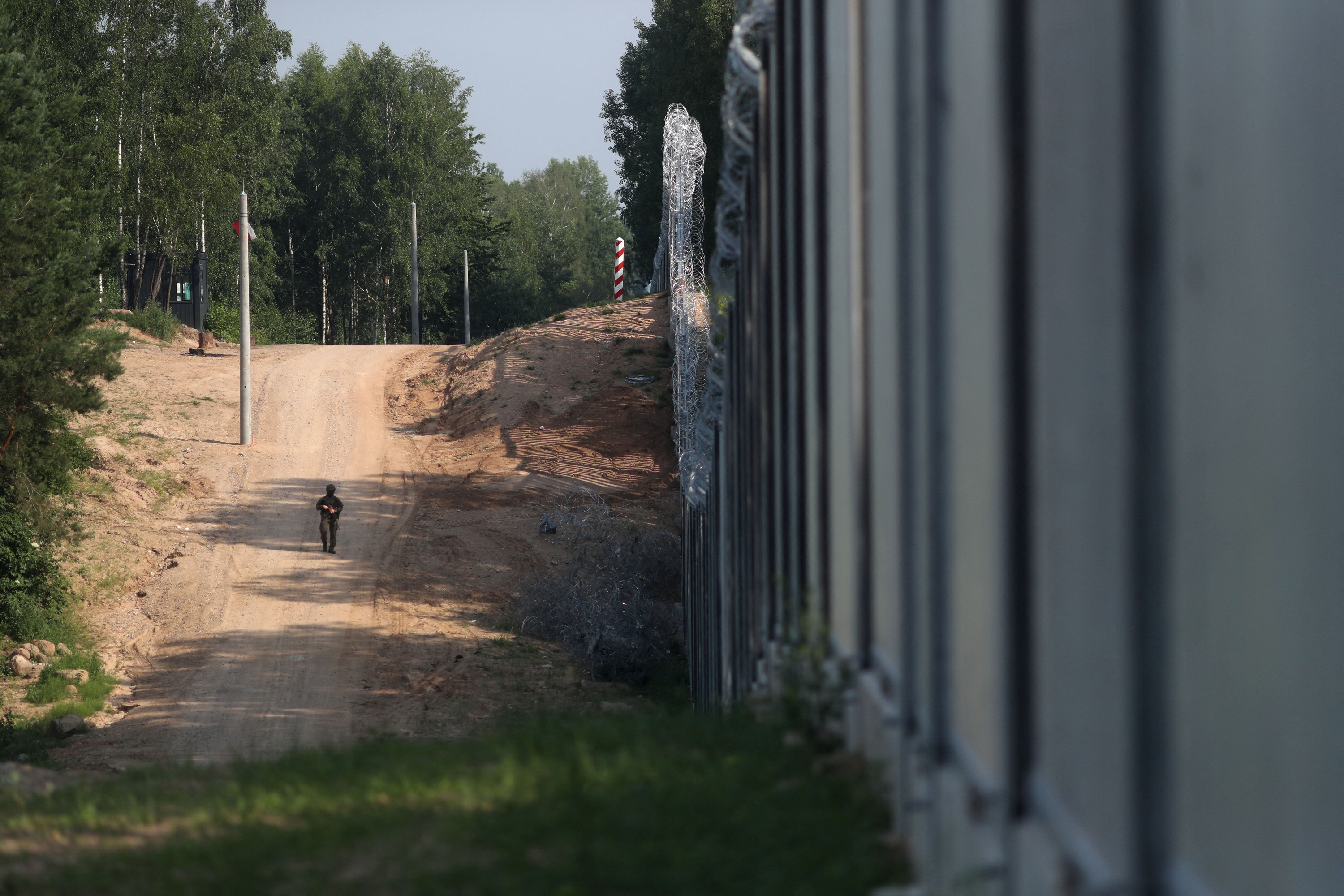 Soldier patrols by the wall erected to prevent migrant crossings on the Polish-Belarusian border, near Kuznica