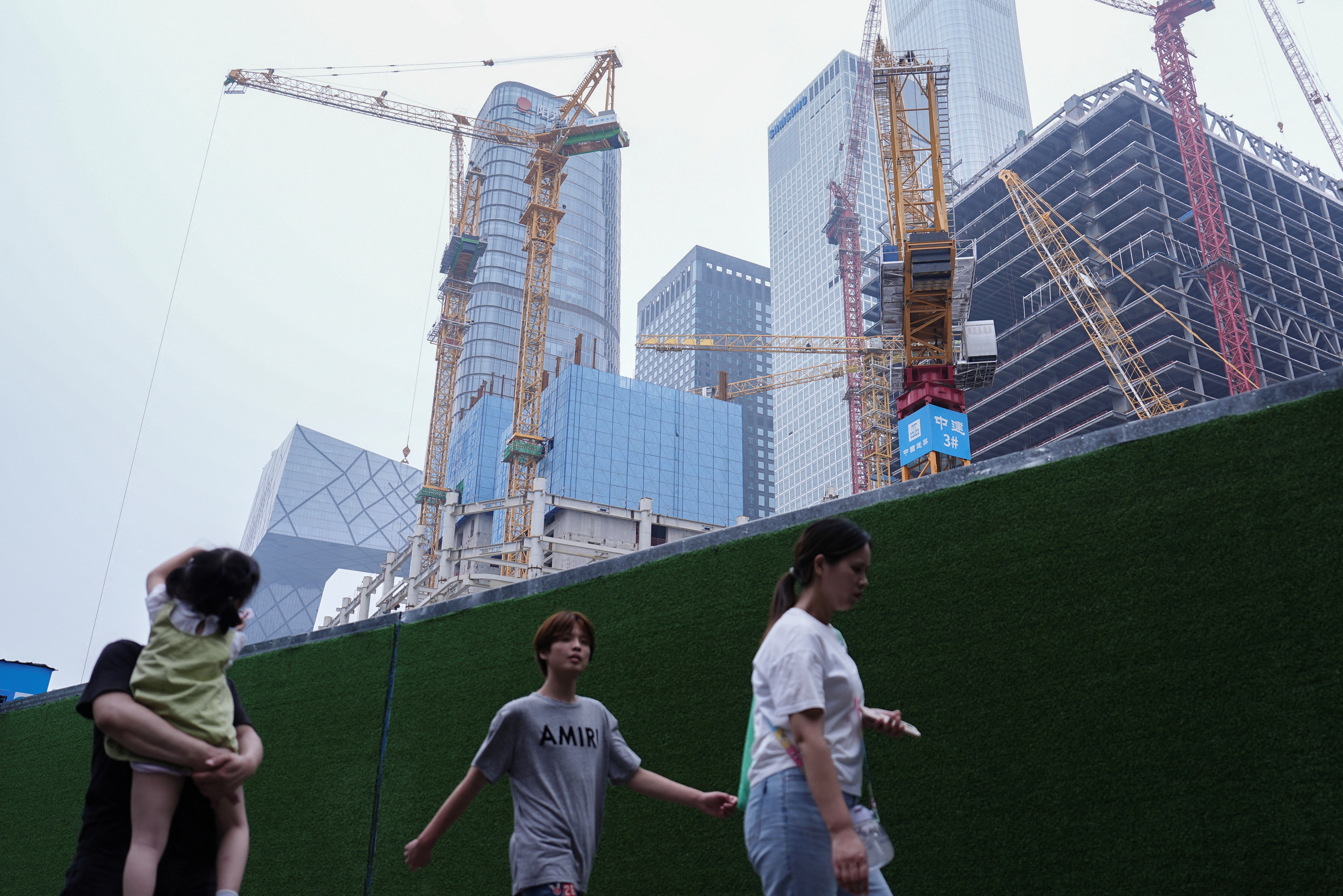 People walk past a construction site in Beijing's Central Business District (CBD)