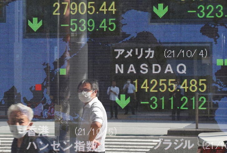 People wearing protective masks amid the coronavirus disease (COVID-19) outbreak are reflected on an electronic board displaying Japan's Nikkei and U.S. Nasdaq index outside a brokerage in Tokyo, Japan, October 5, 2021. REUTERS/Kim Kyung-Hoon