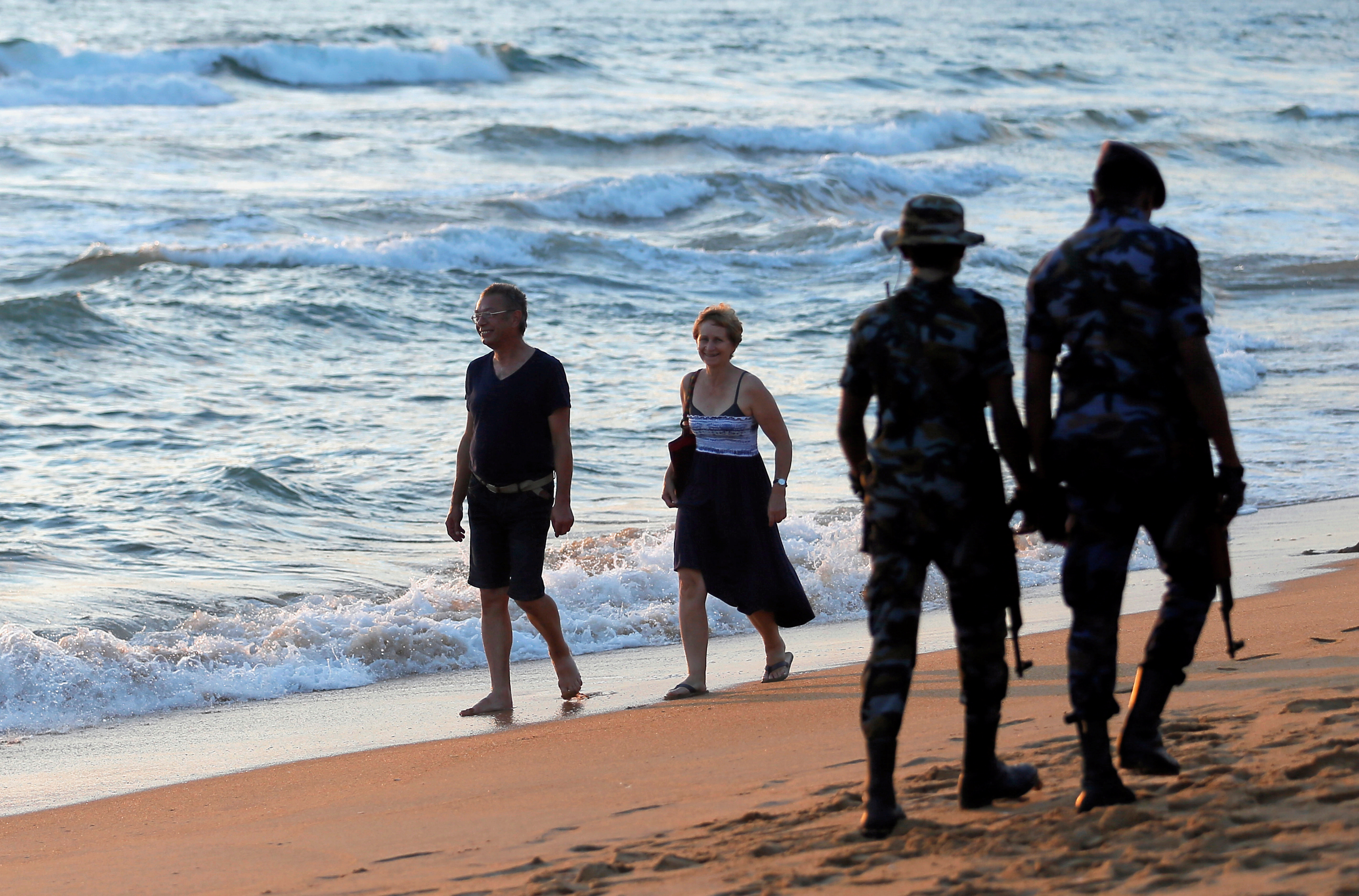 Tourists walk on a beach in Colombo
