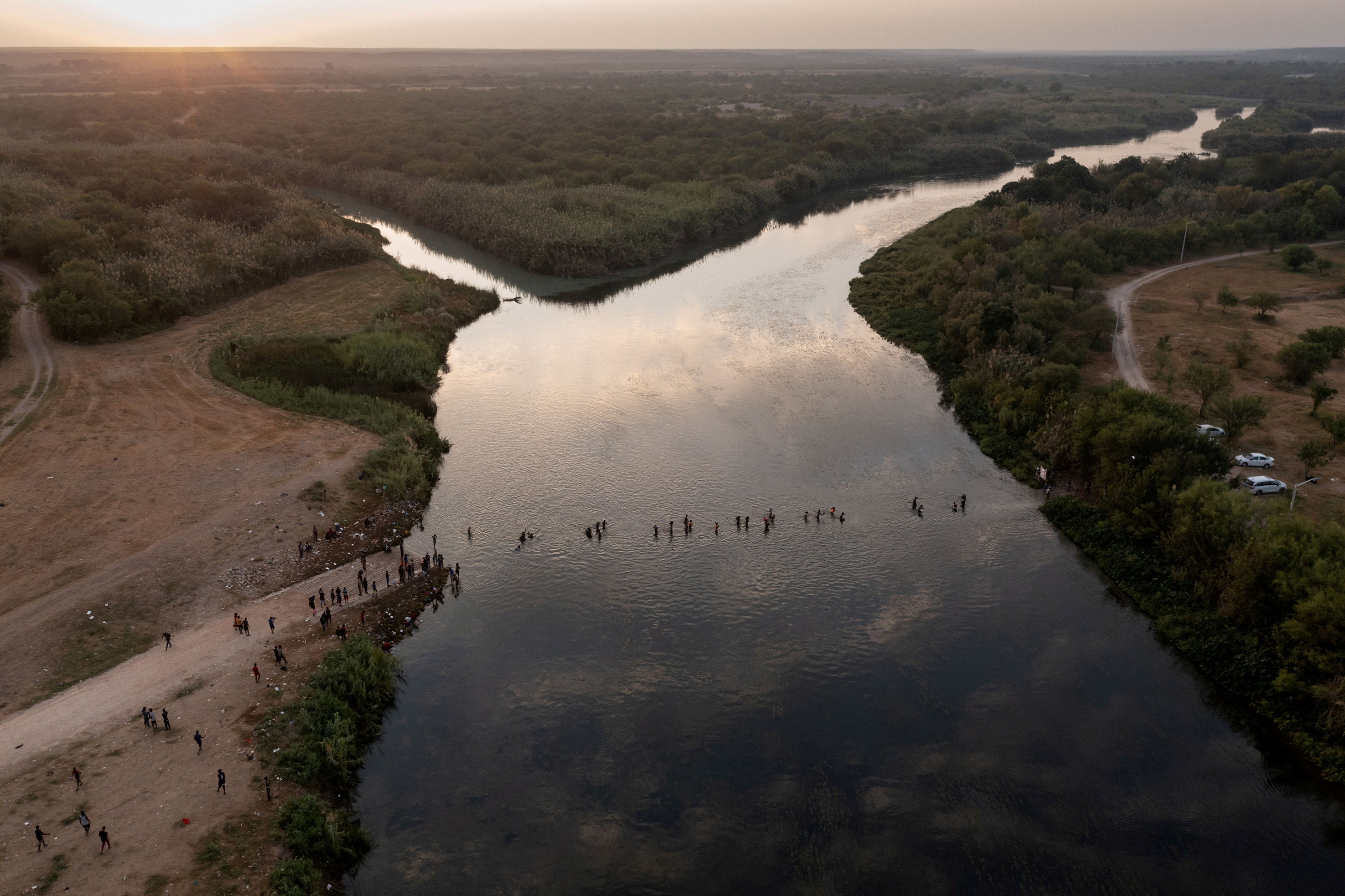Migrants seeking refuge in United States cross the Rio Grande river, with bags and children in tow, back into Ciudad Acuna, Mexico from their camp in Del Rio, Texas, U.S. September 21, 2021. Picture taken with a drone. REUTERS/Adrees Latif//File Photo