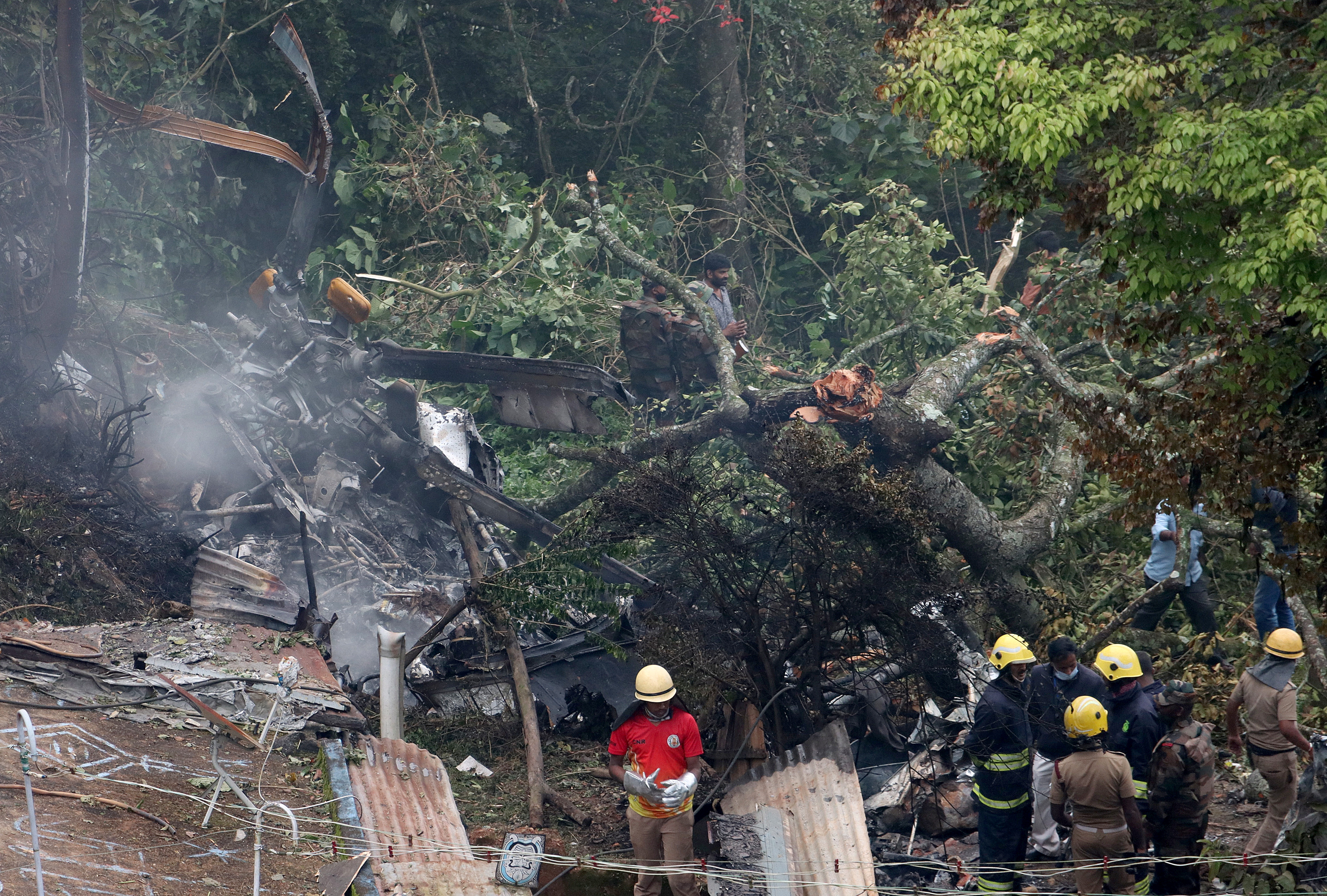 Rescuers stand near the debris of the Russian-made Mi-17V5 helicopter after it crashed near the town of Coonoor in the southern state of Tamil Nadu, India, December 8, 2021. REUTERS/Stringer NO ARCHIVES. NO RESALES.