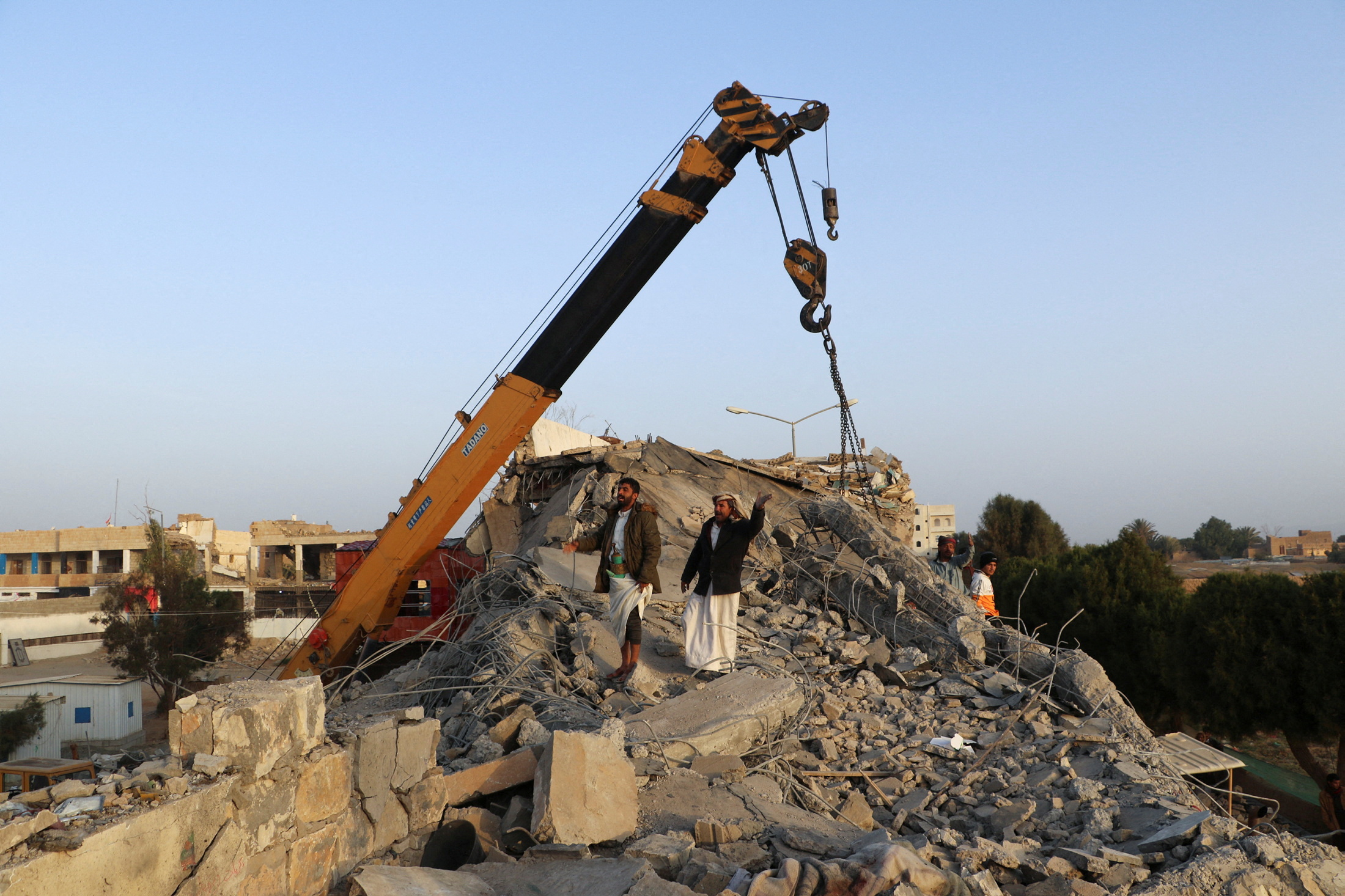 Rescuers use a crane to remove collapsed concrete roof of a detention center hit by air strikes in Saada