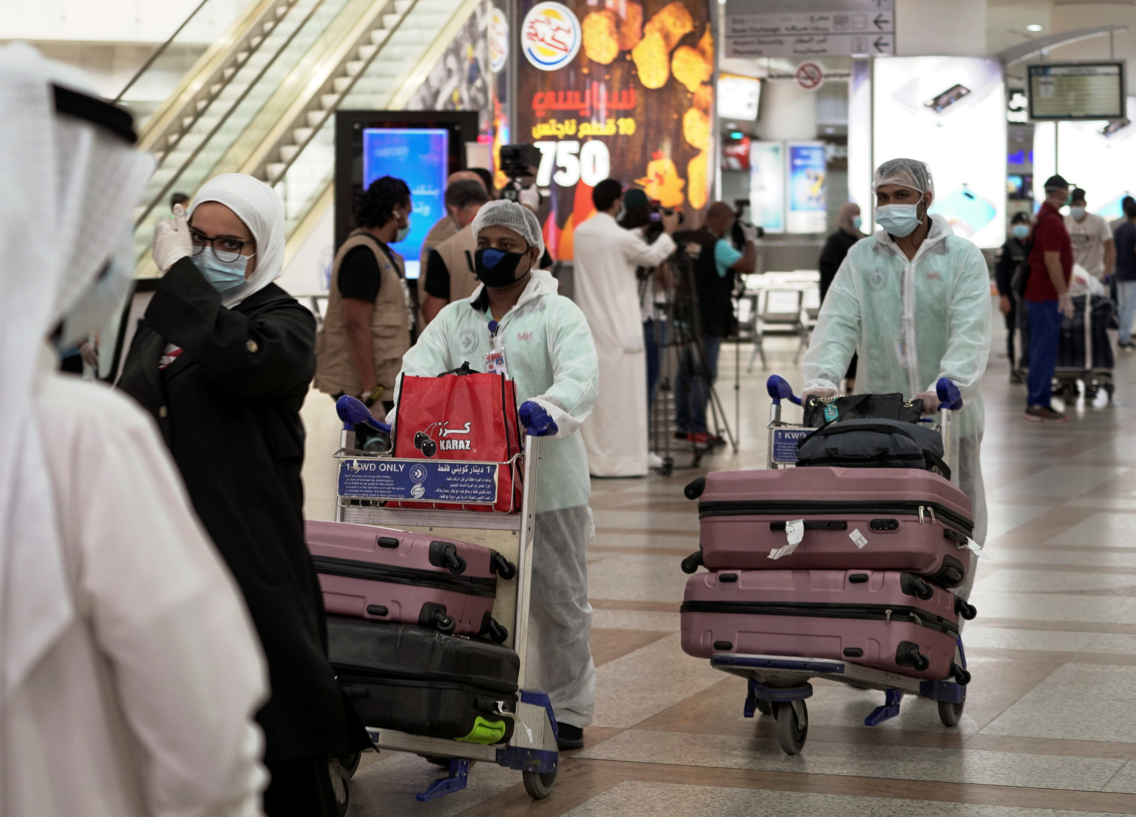Repatriated Kuwaitis from Amman, wearing protective face masks and suits, are seen after arriving at the Kuwait Airport, in Kuwait City