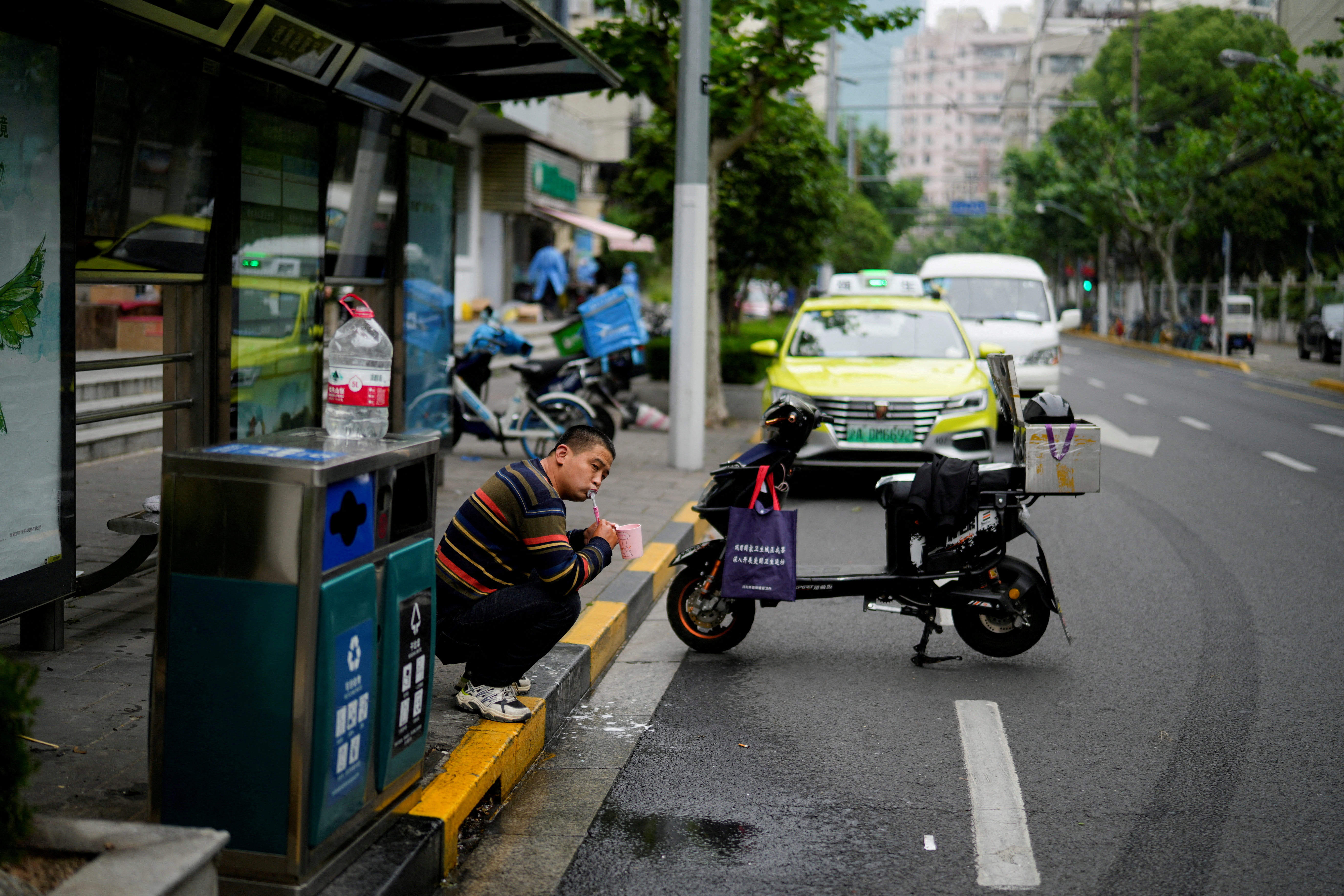A delivery worker brushes his teeth on a street in Shanghai