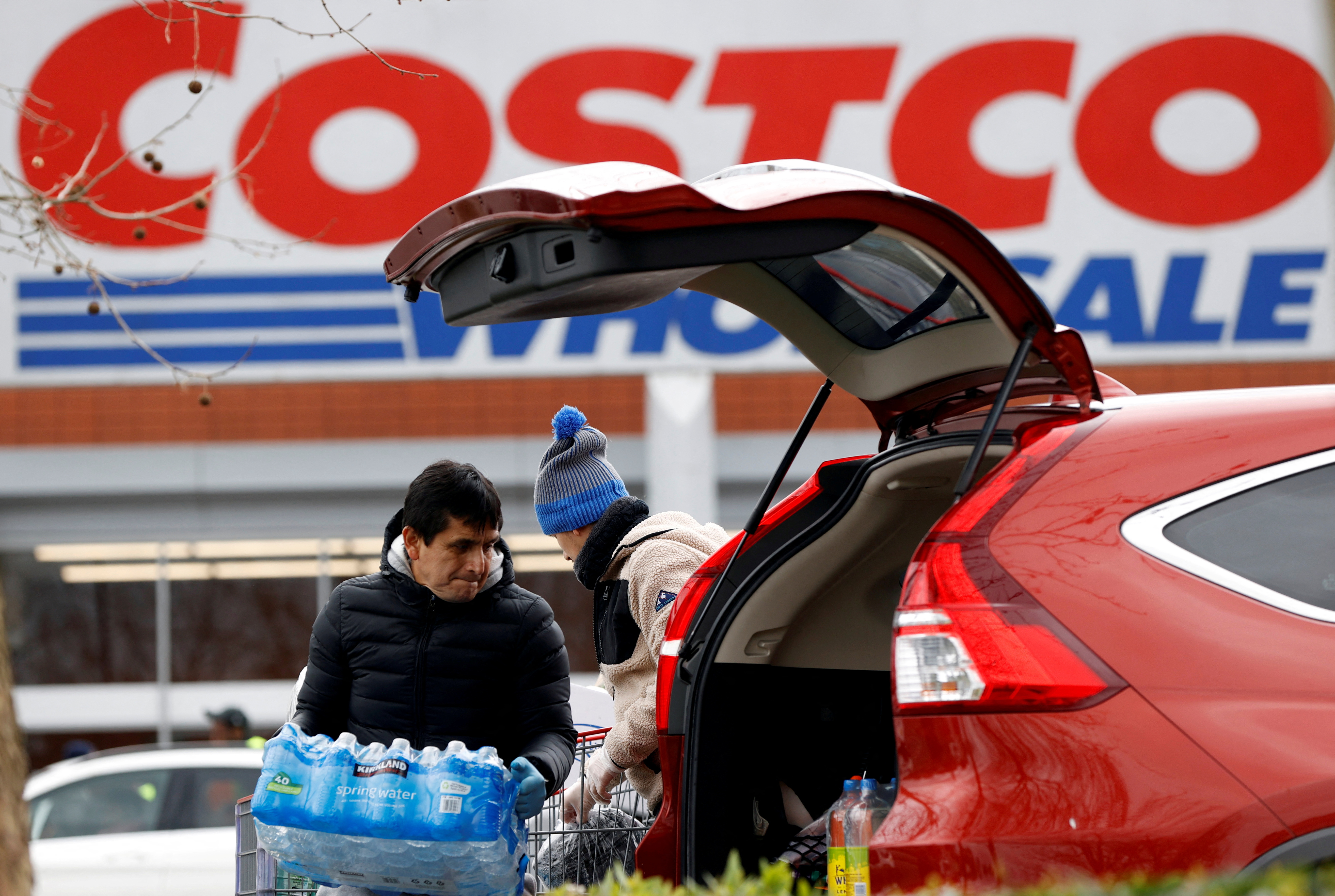 A shopper loads a car with bottled water at a Costco Wholesalers in Chingford