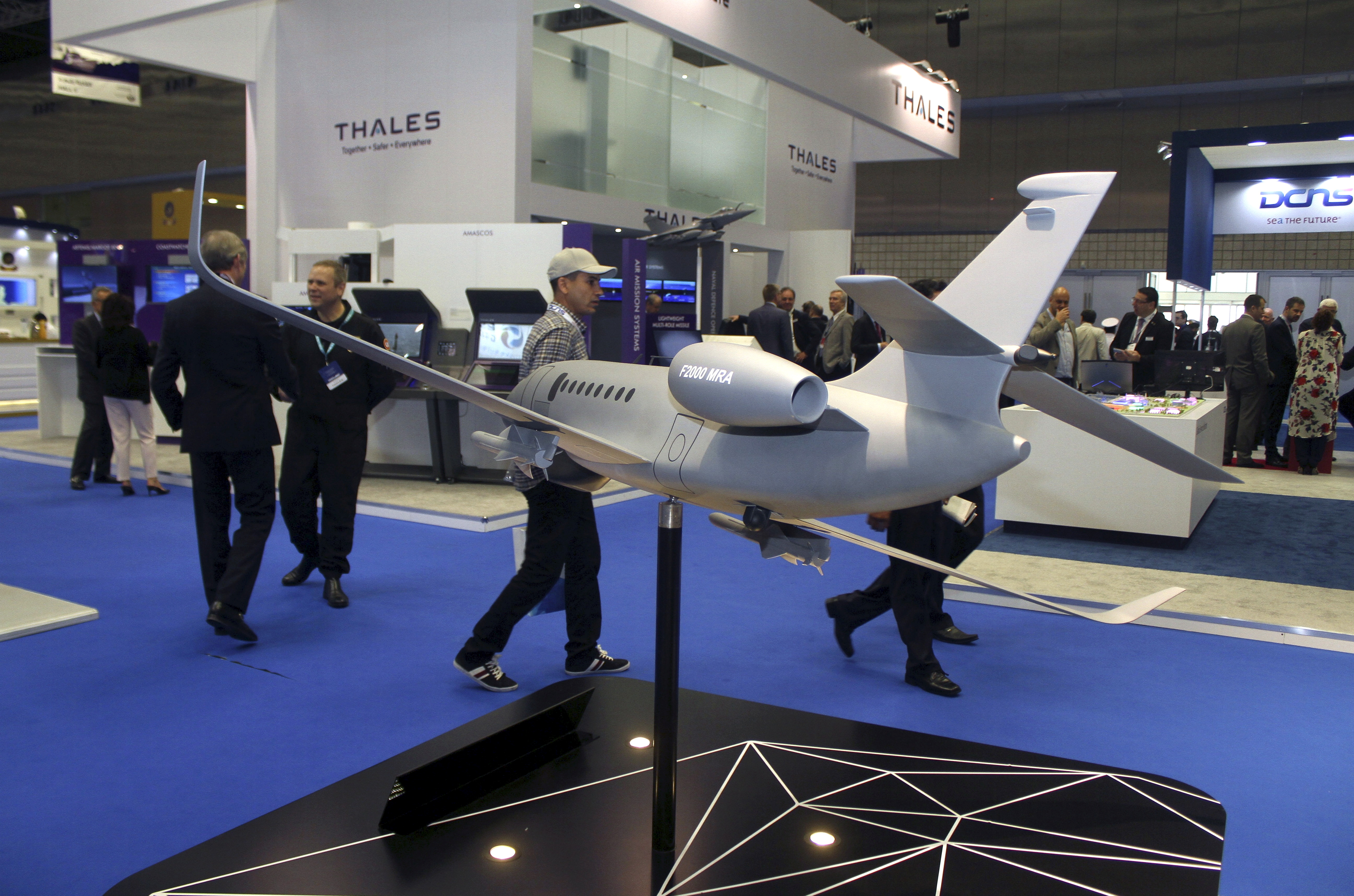 Visitors walk next to model of Dassault Falcon 2000 MRA aircraft during Doha International Maritime Defence Exhibition