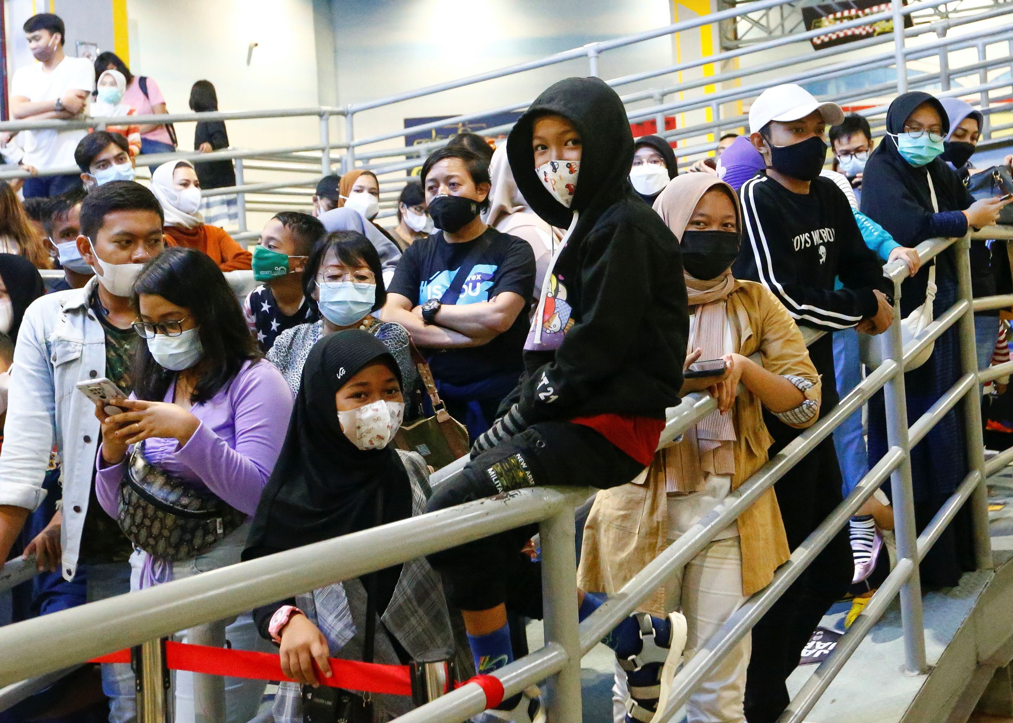 People wearing protective face masks wait for their turn to ride go-karts at Trans Studio, in Jakarta