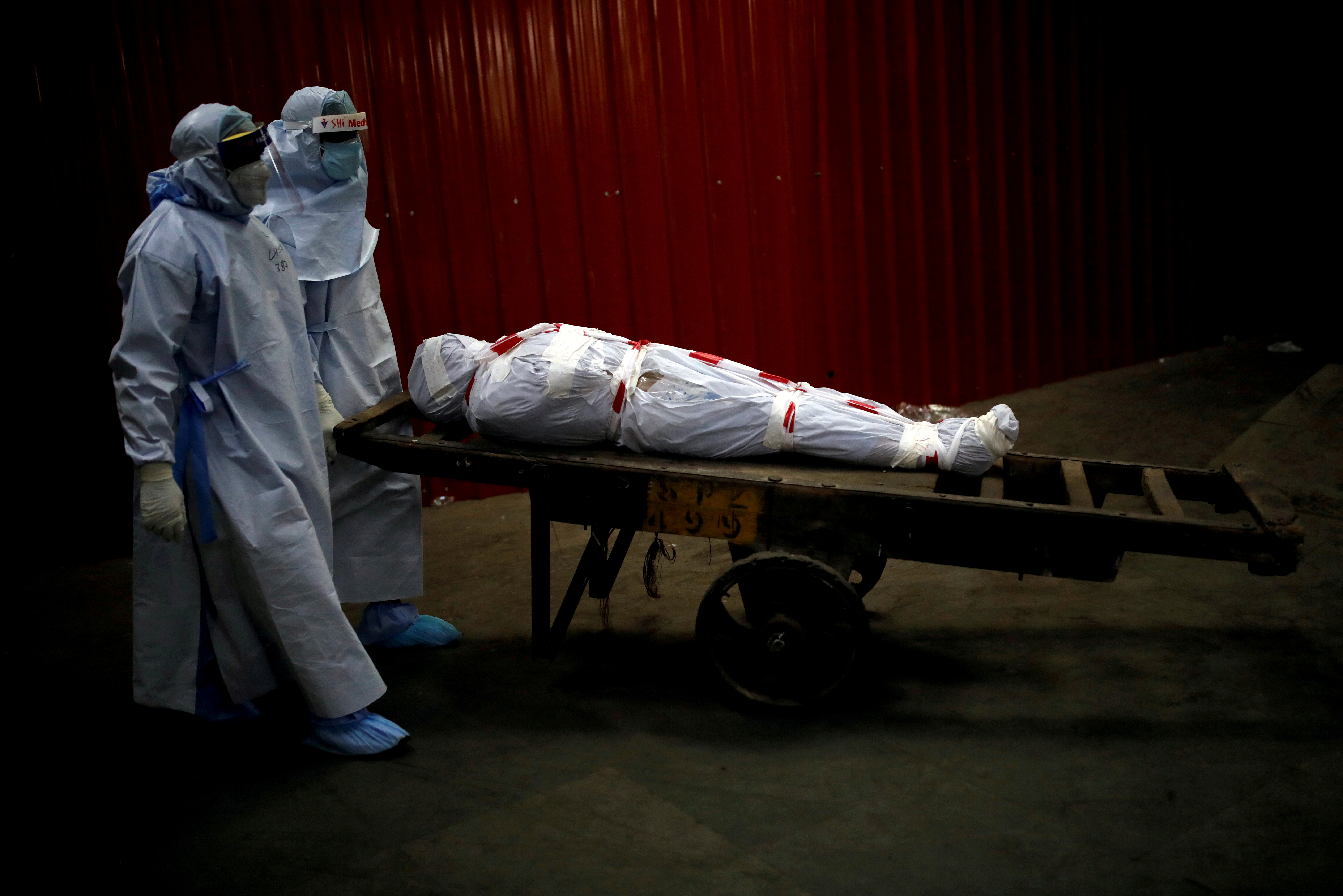Health workers carry the body of a man who died due to the coronavirus disease in New Delhi