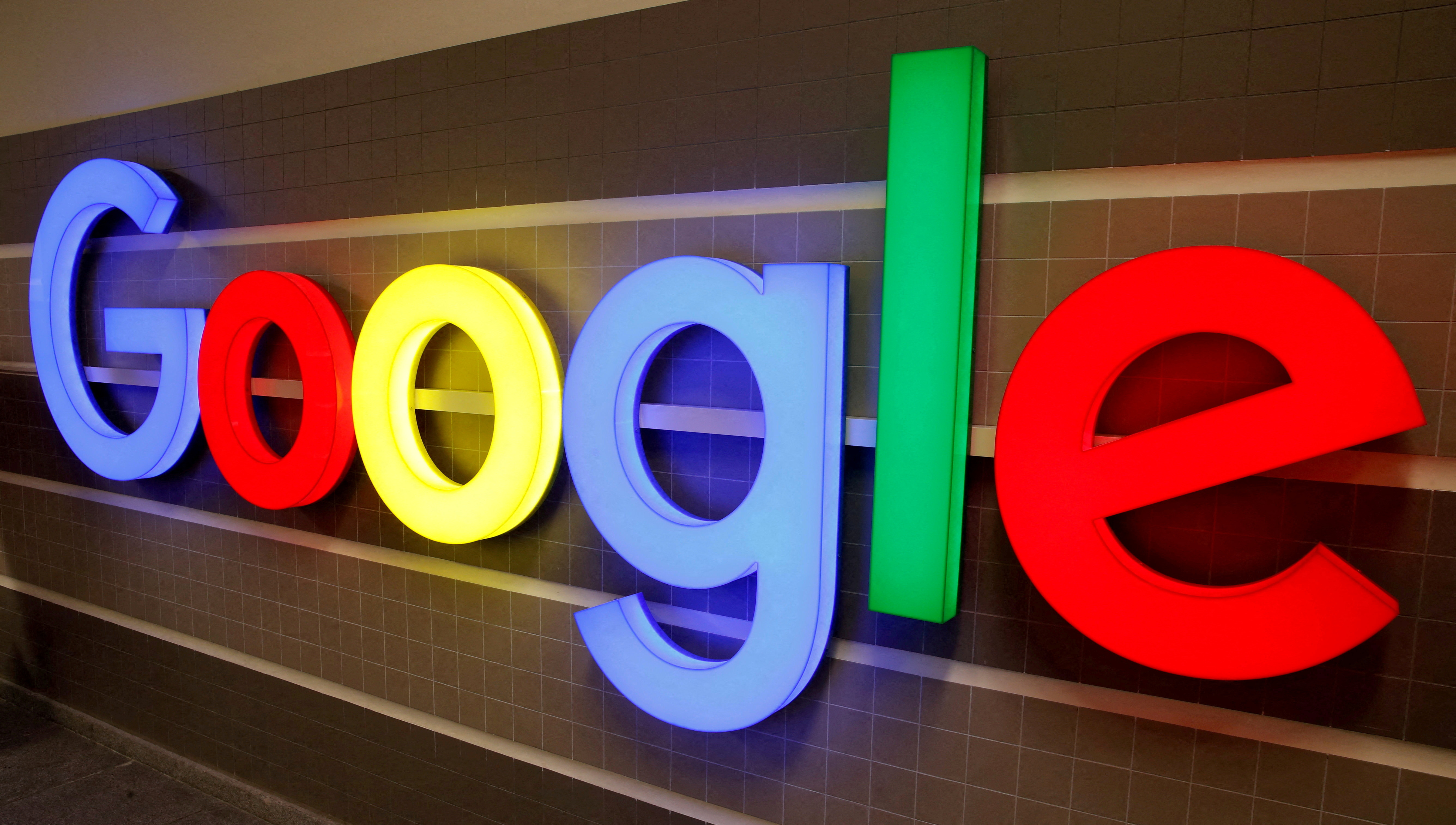 An illuminated Google logo is seen inside an office building in Zurich