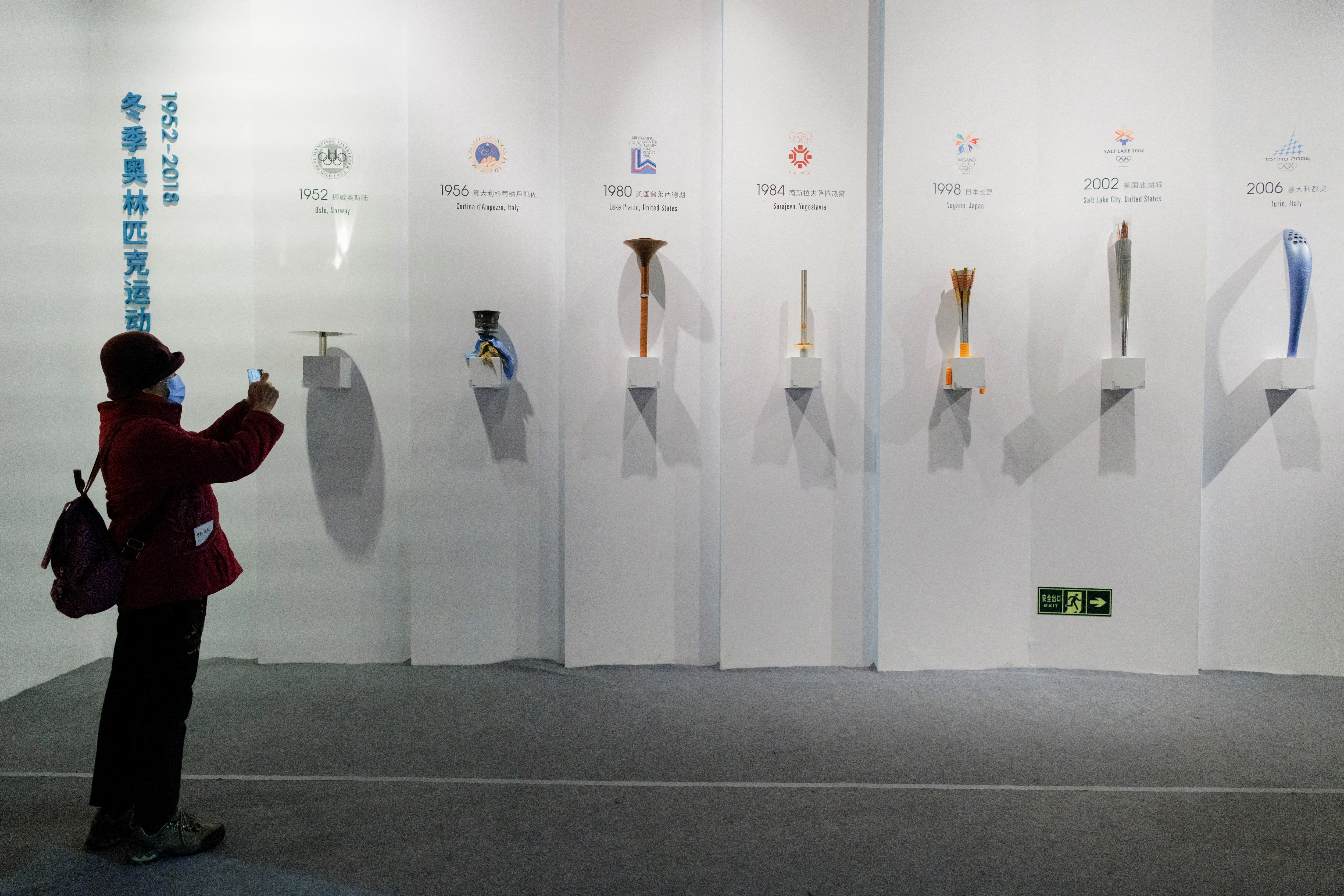 A woman takes pictures of Olympic torches of past Games at an exhibition at the Capital Museum ahead of the Beijing 2022 Winter Olympics in Beijing