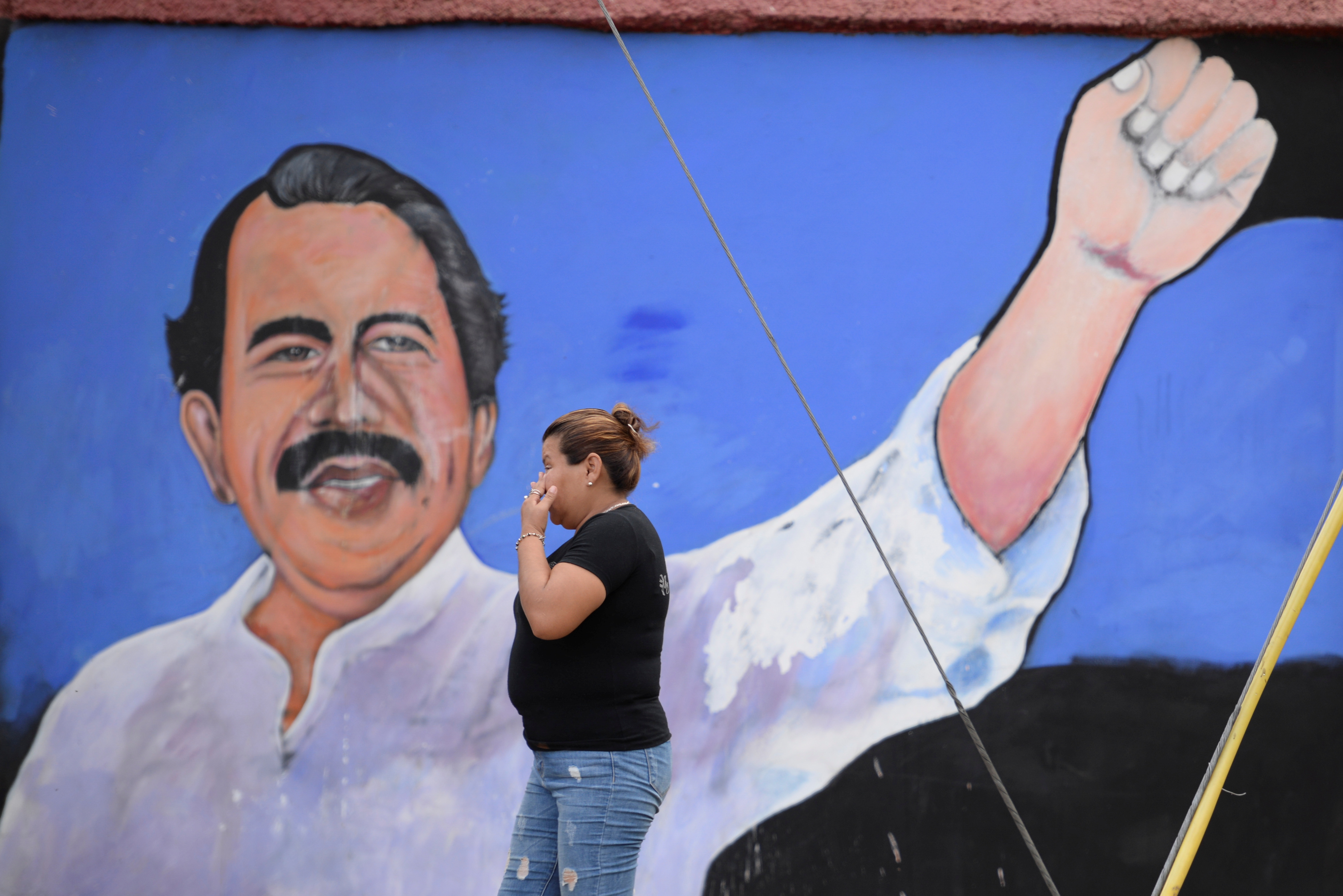 Woman walks by mural depicting Nicaragua's President Ortega in Managua