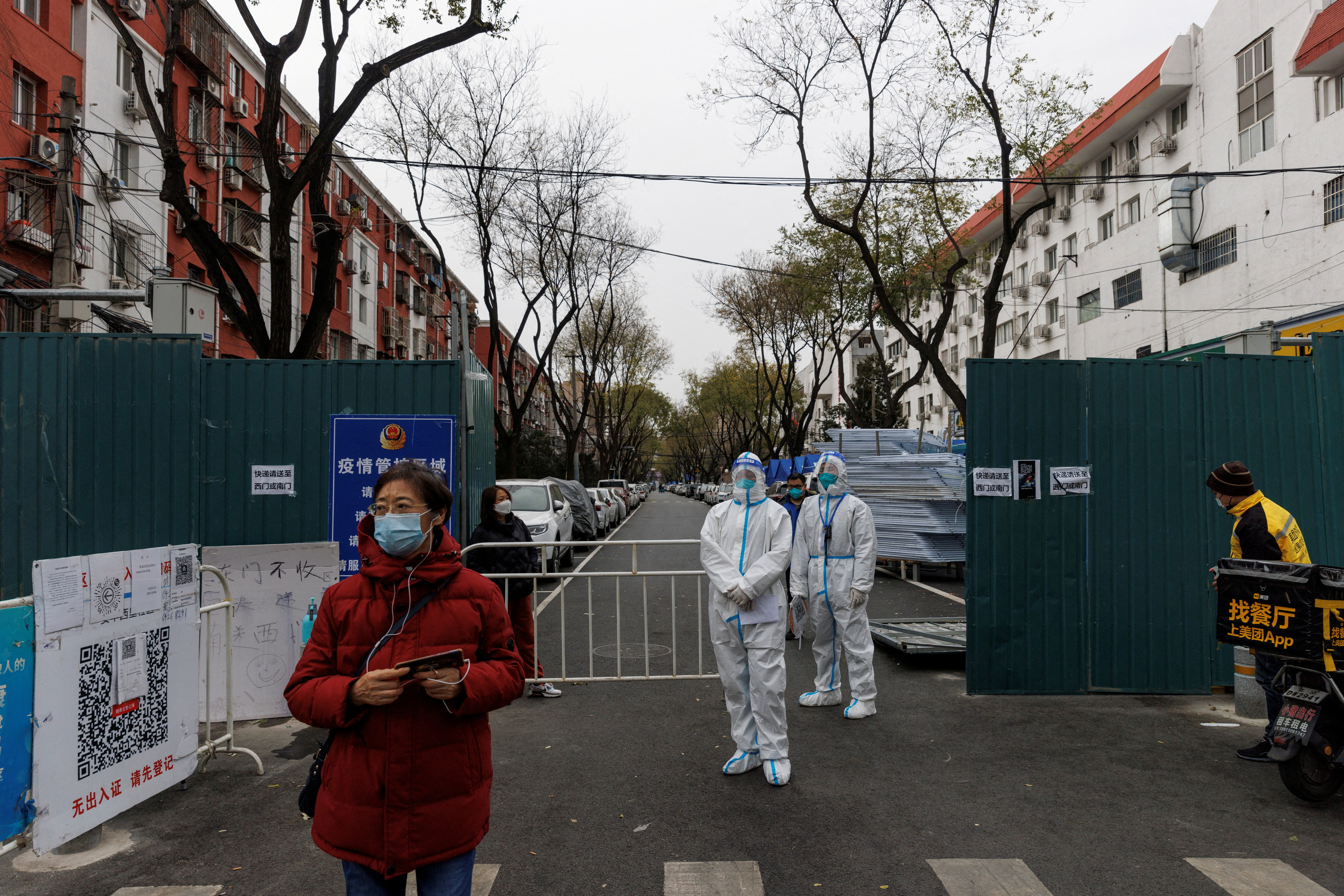 Epidemic-prevention workers in protective suits stand guard at a residential compound as COVID-19 outbreaks continue in Beijing