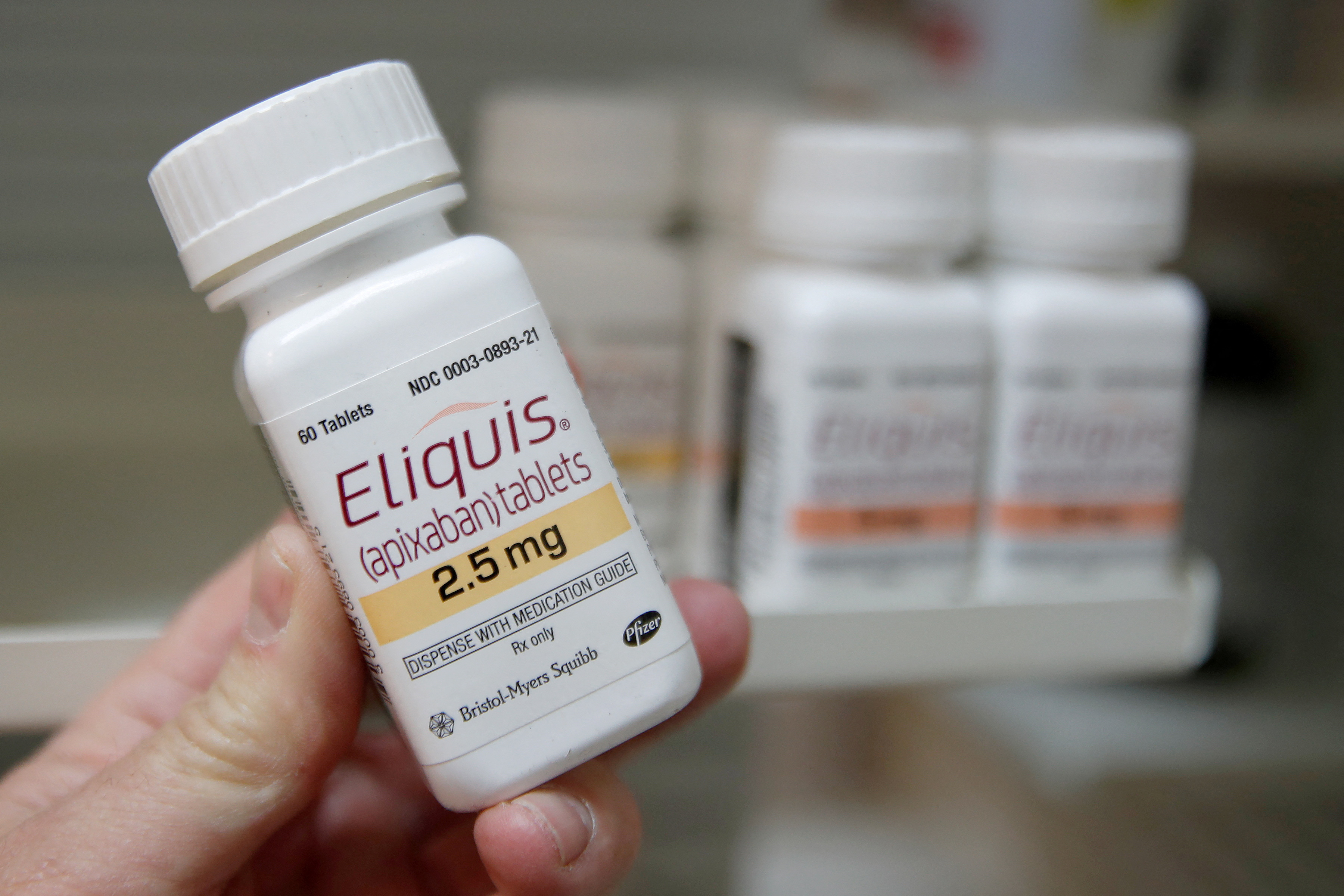 A pharmacist holds a bottle of the drug Eliquis, made by Pfizer and Bristol Myers Squibb , at a pharmacy in Provo