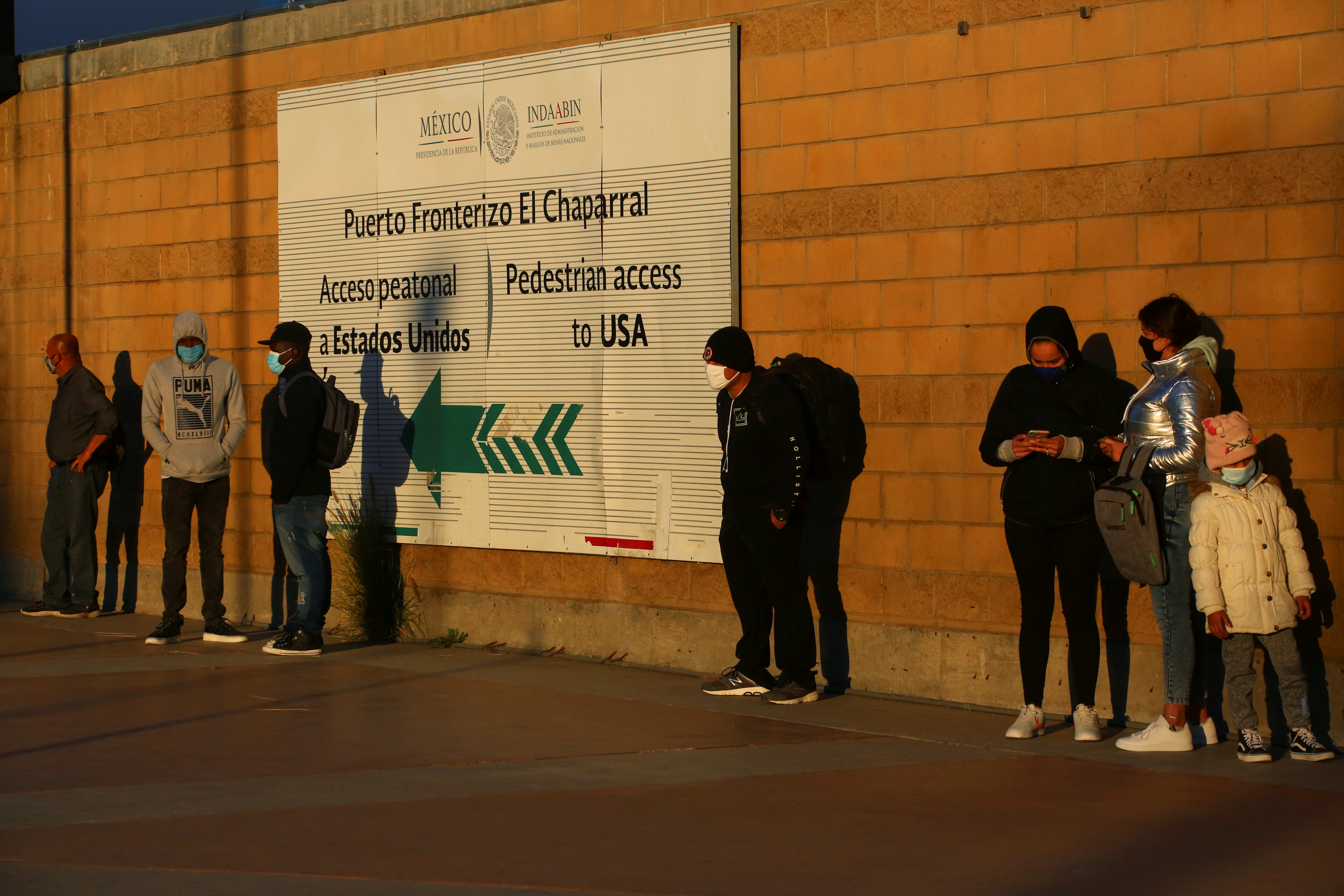 Migrants queue at the El Chaparral border crossing point to seek asylum in the U.S., in Tijuana