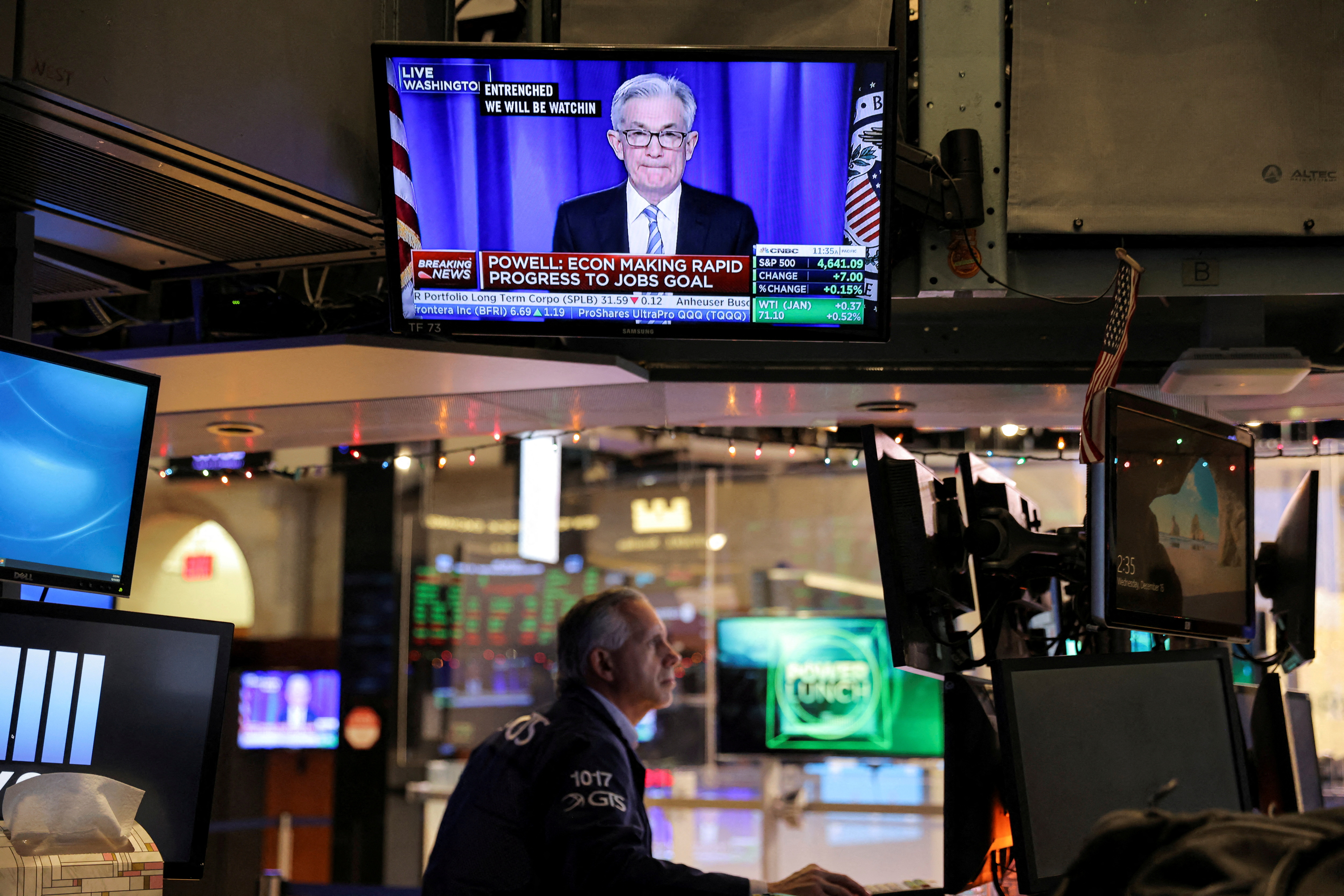 Federal Reserve Chair Jerome Powell is seen delivering remarks on a screen as a trader works on the trading floor at the New York Stock Exchange (NYSE) in Manhattan, New York City, U.S., December 15, 2021. REUTERS/Andrew Kelly/File Photo