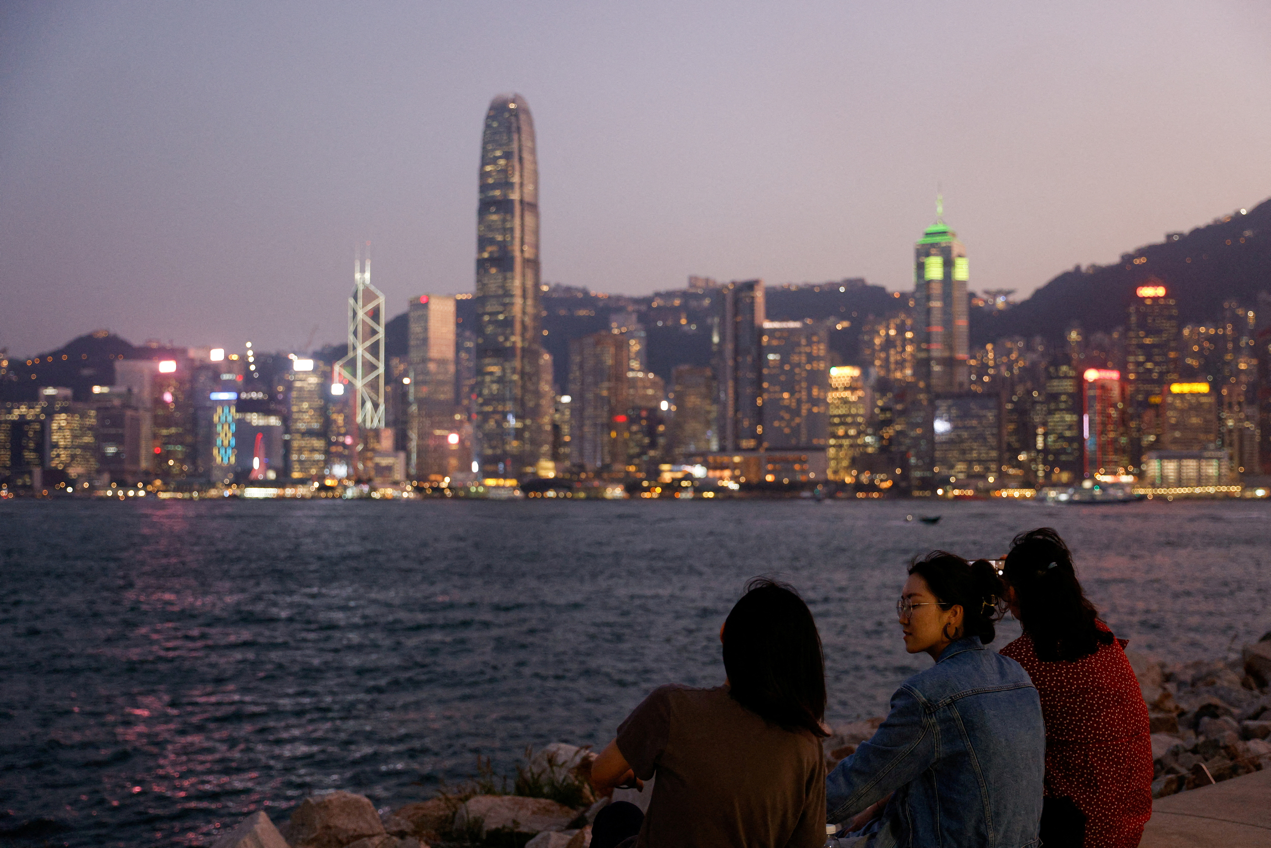 Women talk at West Kowloon Cultural District near the Victoria Harbour during sunset in Hong Kong