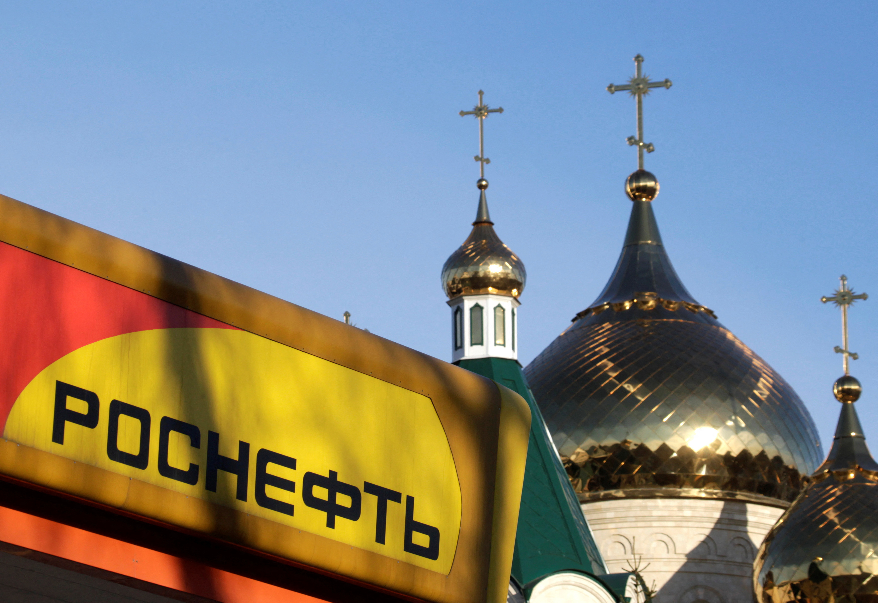 The logo of Russia's top crude producer Rosneft is seen on a gasoline station near a church in Stavropol