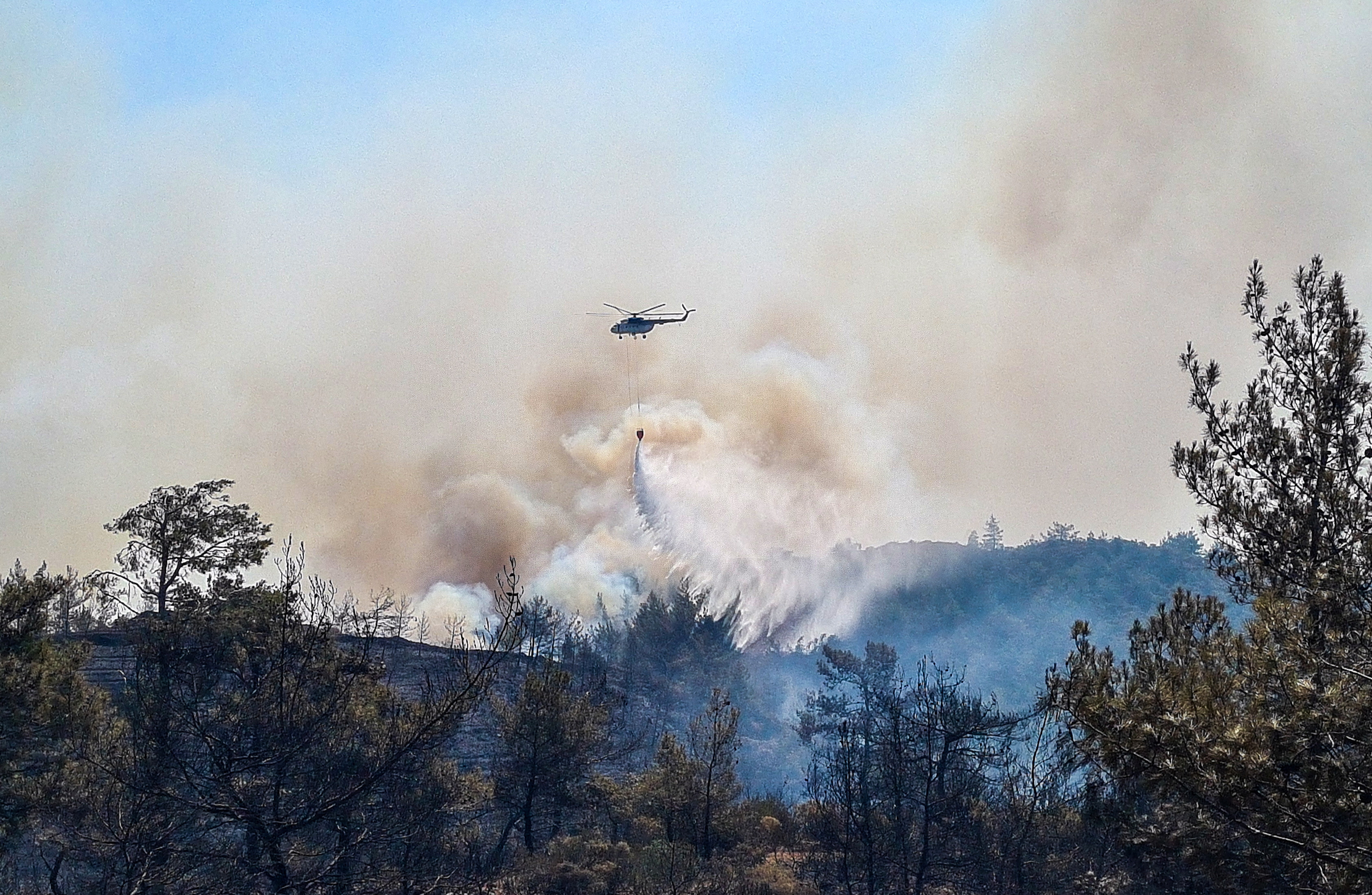 A firefighting helicopter drops water on a wildfire near Marmaris