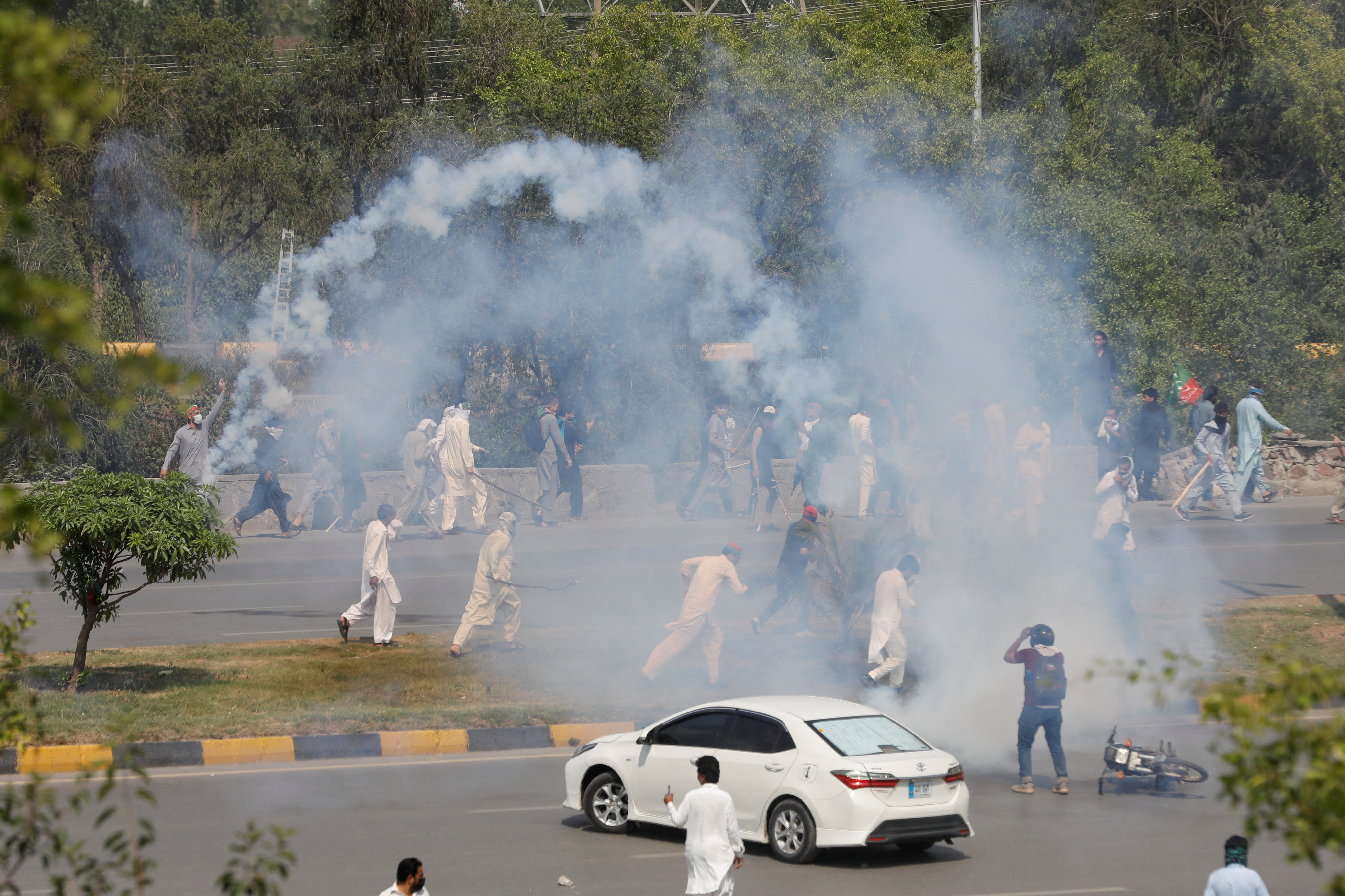 People run amid the tear gas smokes, in Rawalpindi