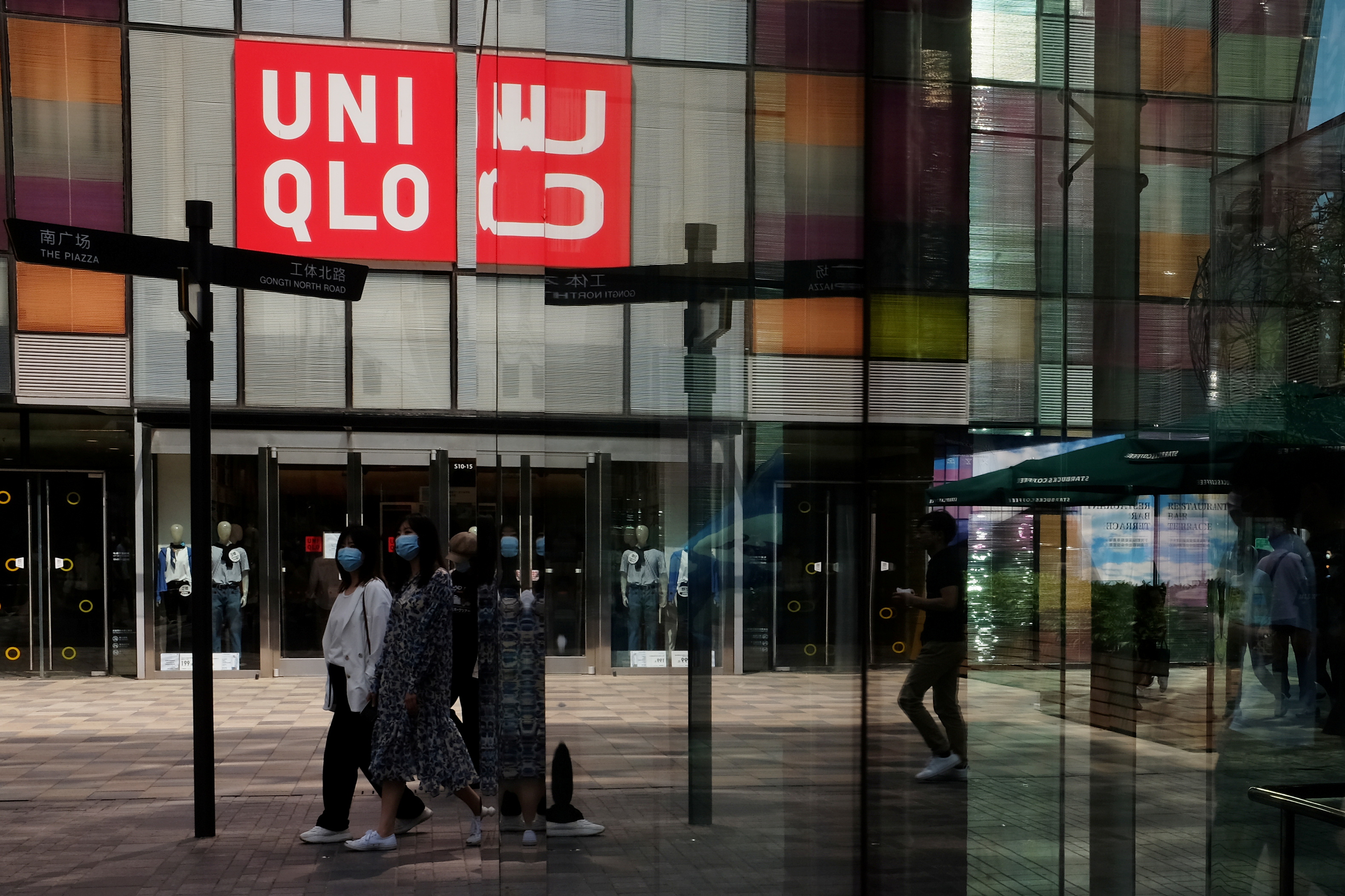 Women wearing face masks, following the coronavirus disease (COVID-19) outbreak, walk past a store of Fast Retailing's fashion chain Uniqlo at a shopping complex in Beijing, China May 24, 2020. REUTERS/Florence Lo