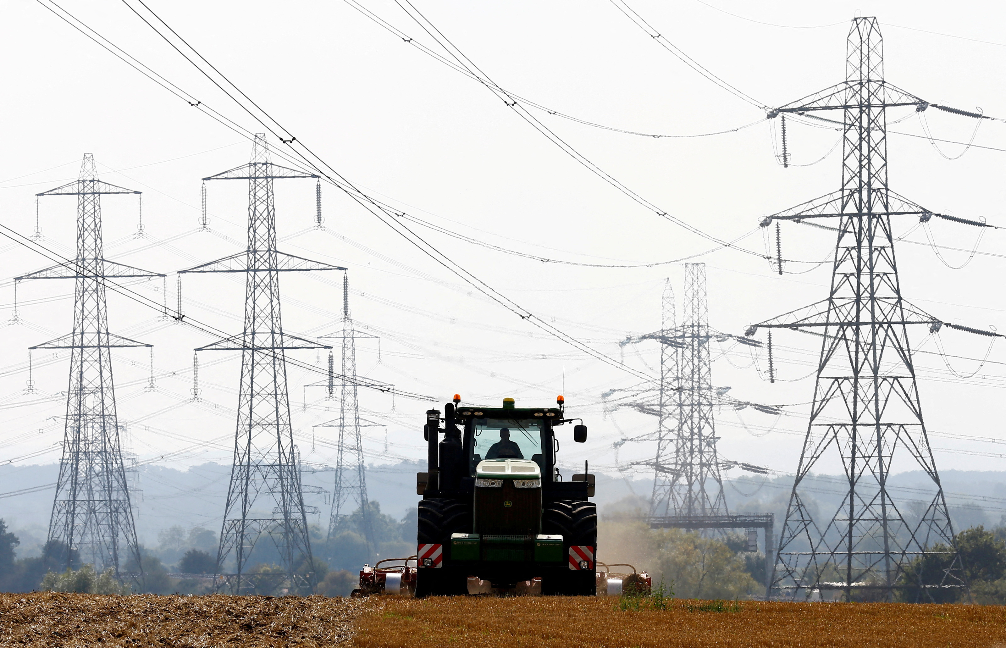 A farmer works in a field surrounded by electricity pylons in Ratcliffe-on-Soar