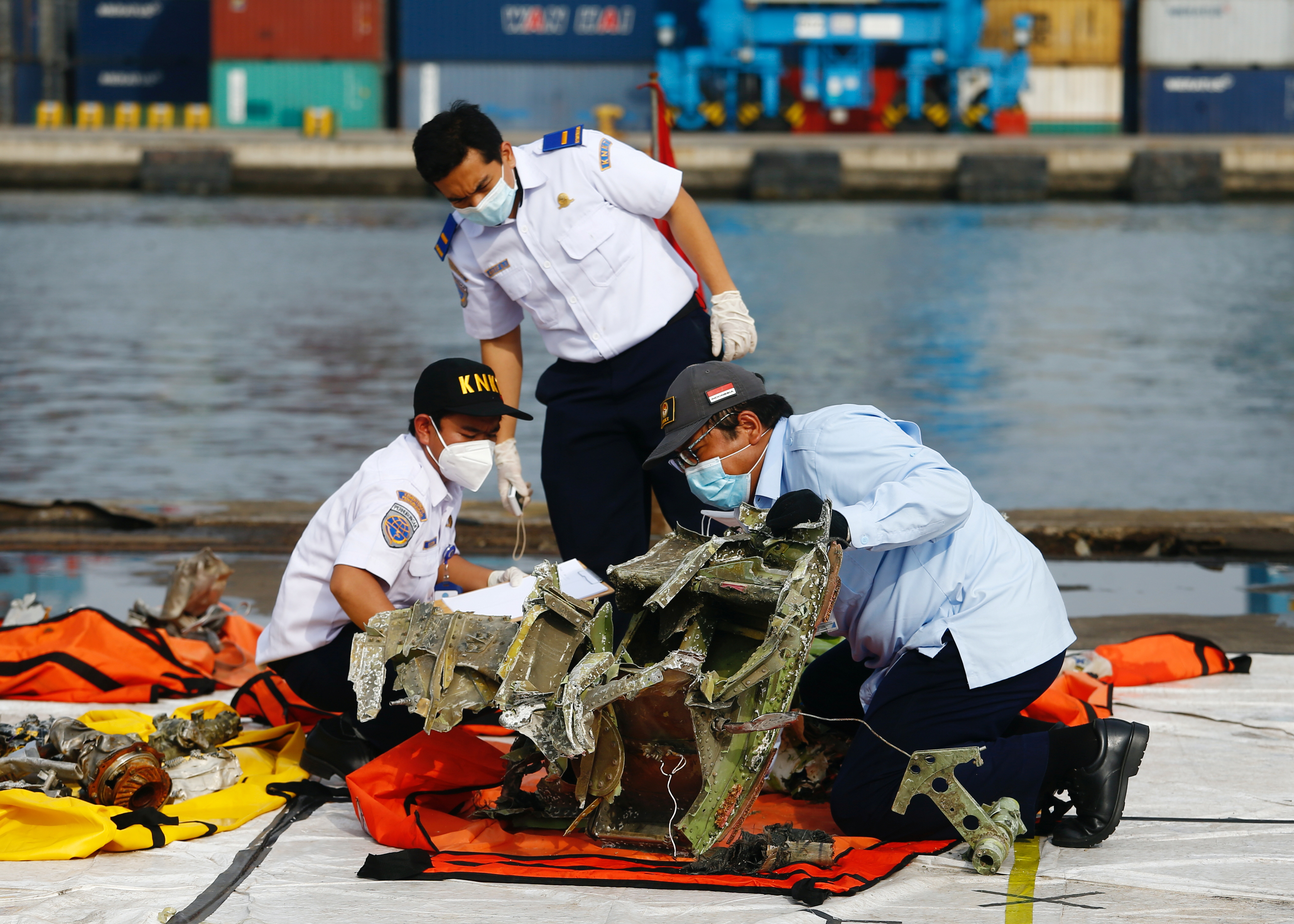 Officers of Indonesia's National Transportation Safety Committee inspect the debris of Sriwijaya Air flight SJ 182, which crashed into the Java Sea, on the last day of its search and rescue operation, at Tanjung Priok port in Jakarta