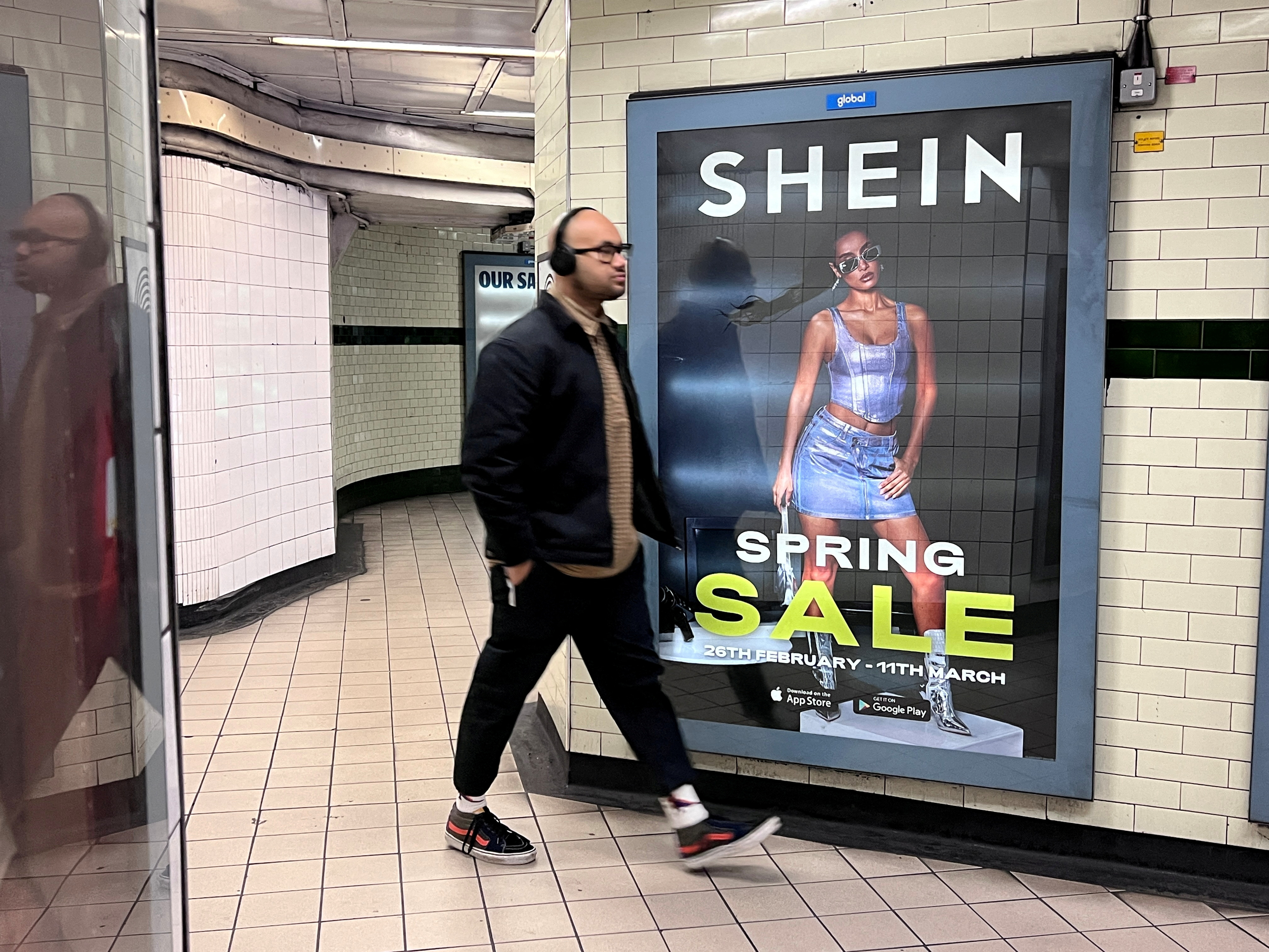 People walk past an advertisement for Shein