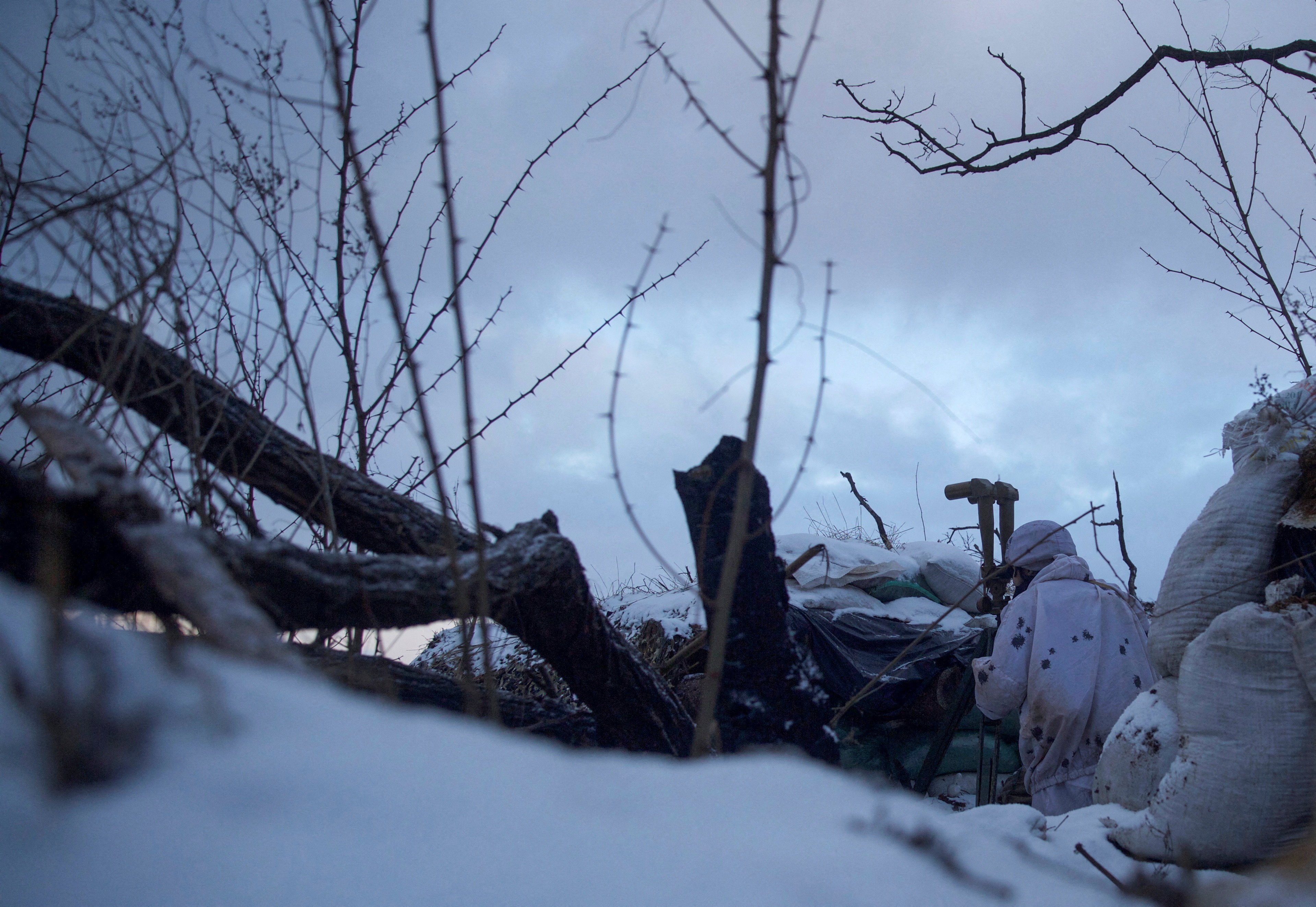 A service member of the Ukrainian armed forces observes the area at combat positions in the Donetsk region